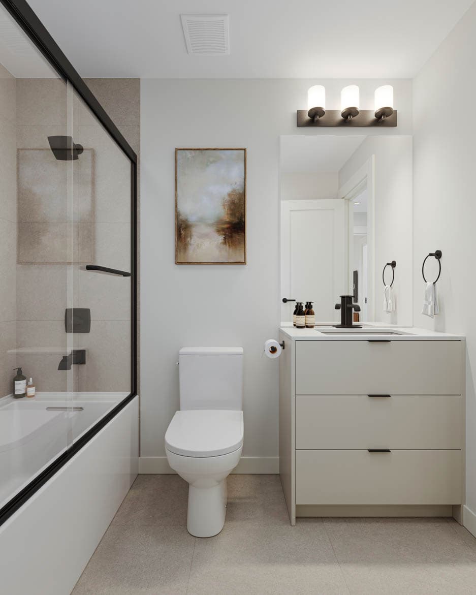 Kin & Kith – A contemporary bathroom with a glass-enclosed bathtub shower combo, single vanity with matte black fixtures, and framed wall art.