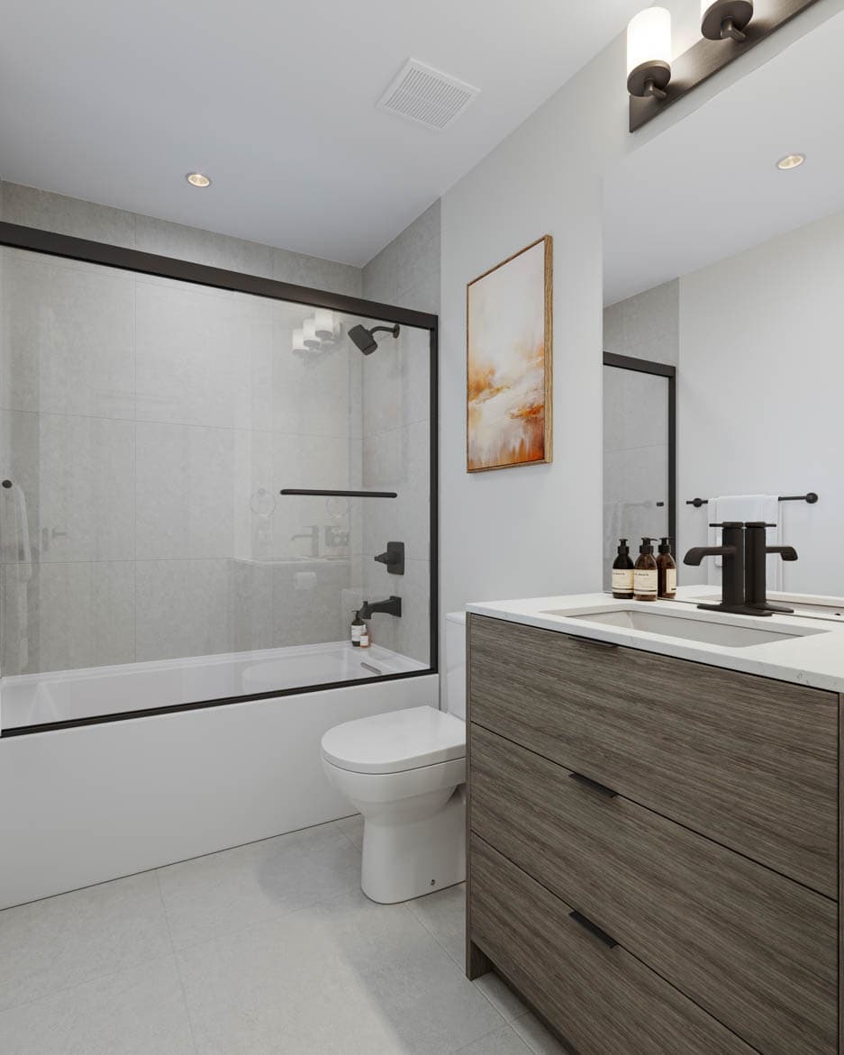 Kin & Kith – A full bathroom featuring a wood grain vanity with white countertop, black tapware, toilet, and glass shower tub combo.