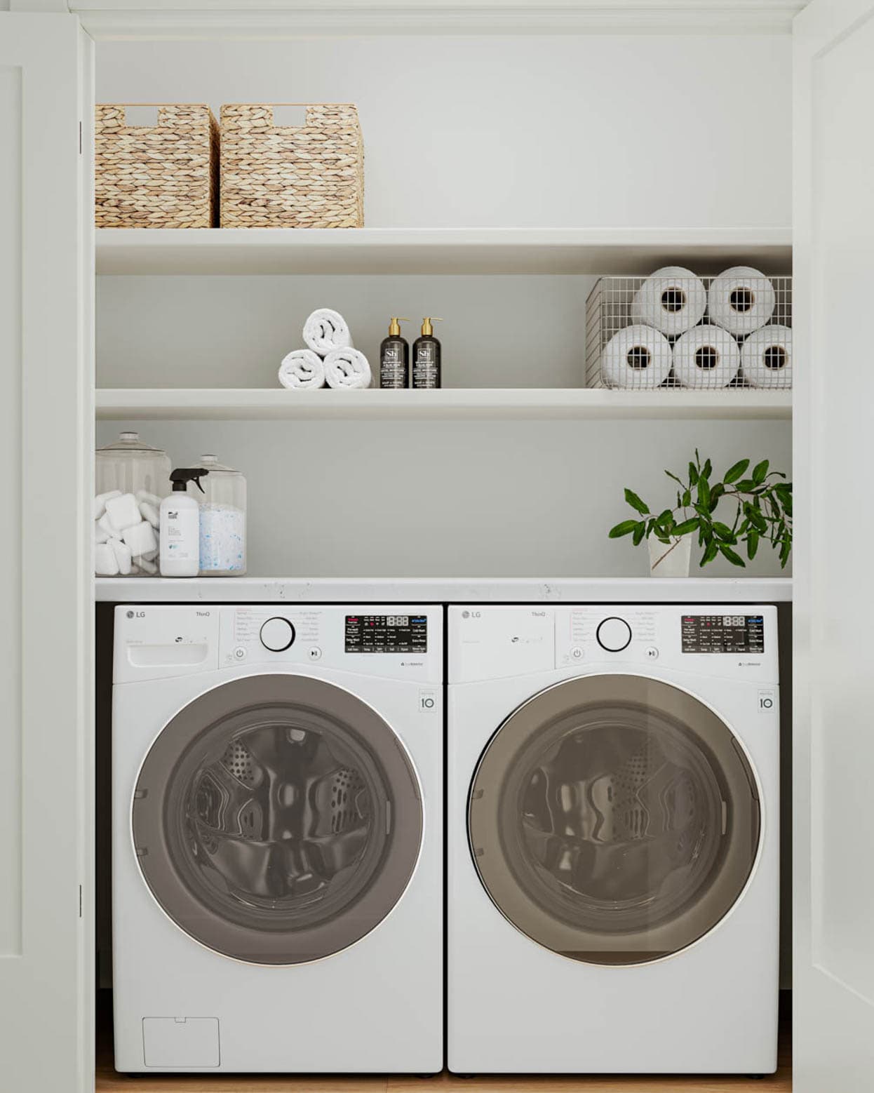Kin & Kith – Laundry closet equipped with side-by-side white front-loading washer and dryer, upper shelving, and storage baskets.