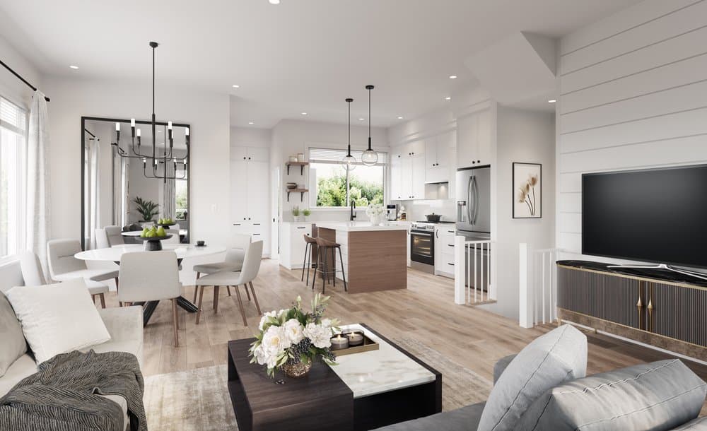 Jasper – Bright open-concept living area featuring a gray sofa, coffee table, and media console alongside a round dining table, with an open kitchen showing white cabinetry, stainless steel appliances, and a wood-faced island.