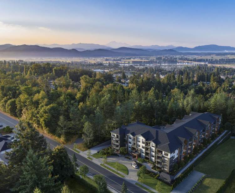 Preston on Fourteenth – Aerial drone view of a low-rise condo building surrounded by forest with mountains and a valley visible in the distance at sunrise.