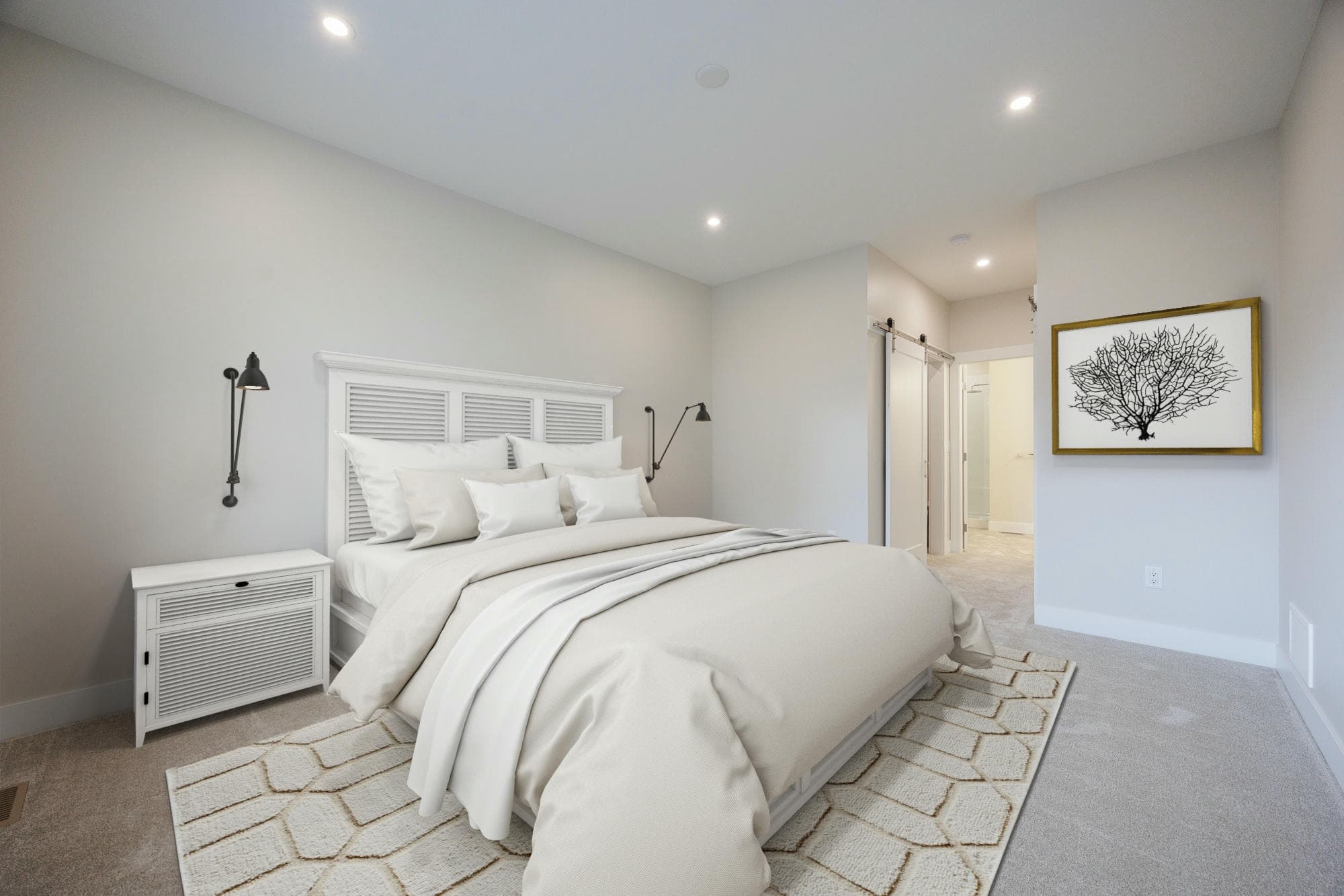 Malloway Village – A bright, neutral-toned bedroom features a bed dressed in white and cream linens with a white louvered headboard, flanked by a matching nightstand and black wall sconces. Carpeted flooring, a patterned area rug, recessed ceiling lights, and framed wall art create a clean and calm atmosphere leading toward an ensuite bathroom.