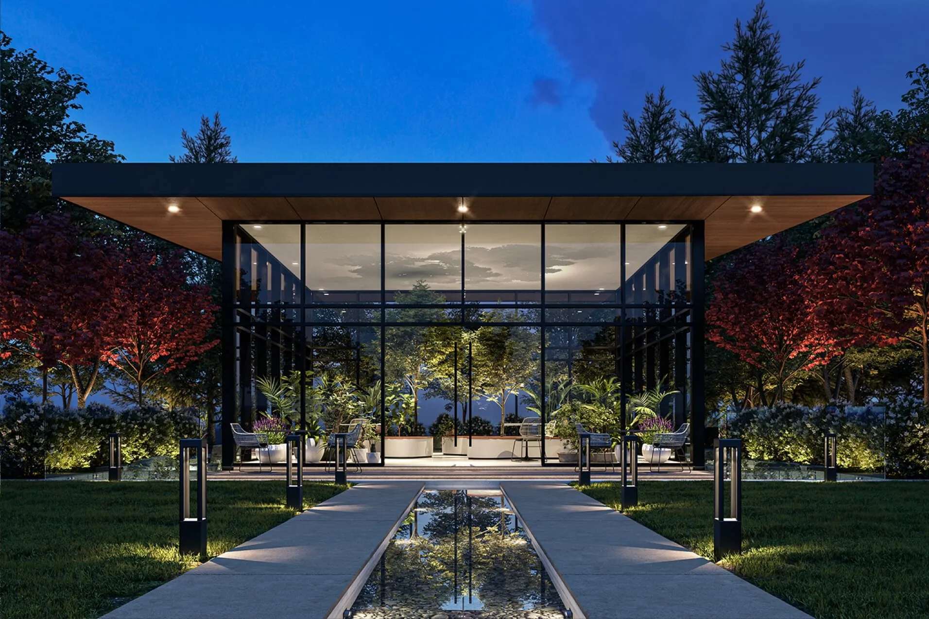 Concord Metrotown – A modern glass-walled pavilion house is illuminated at twilight, surrounded by lush manicured lawn, shrubs, and dark red trees. A linear stone pathway with a shallow water feature bisects the foreground, leading toward the brightly lit indoor garden lounge.