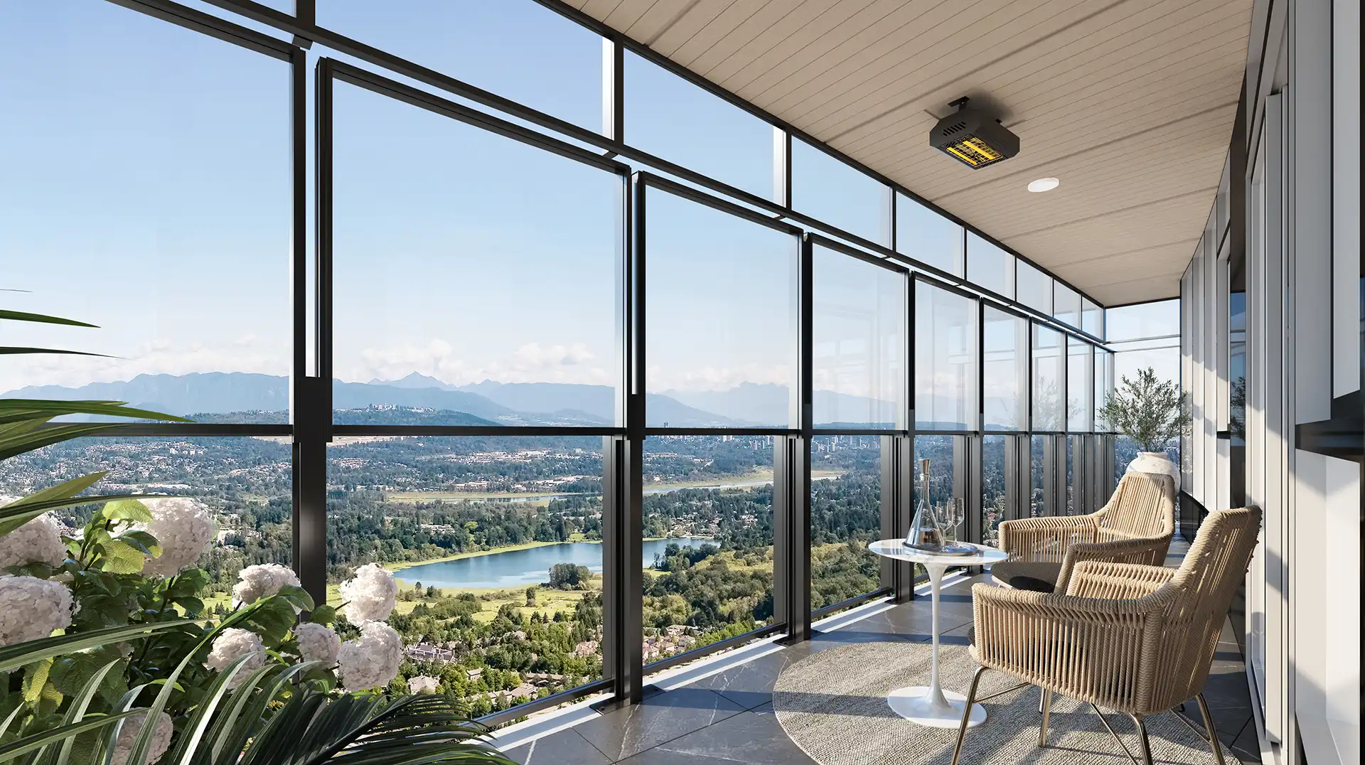 Concord Metrotown – A covered high-rise balcony equipped with retractable glass panels, woven armchair seating, and a small side table overlooking an expansive landscape of forests, a lake, and distant mountains. Sunlight fills the bright, modern space, highlighting an overhead patio heater and potted white hydrangeas in the foreground.