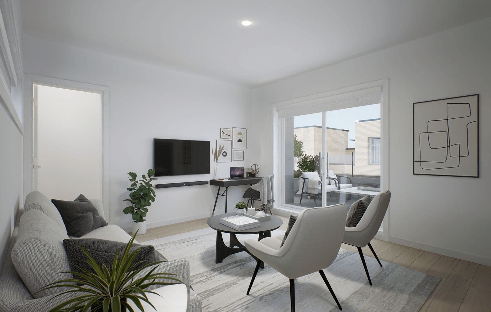 Terza – Living room with a gray sofa, wall-mounted TV, desk, and sliding glass door leading to a balcony overlooking neighboring townhomes.
