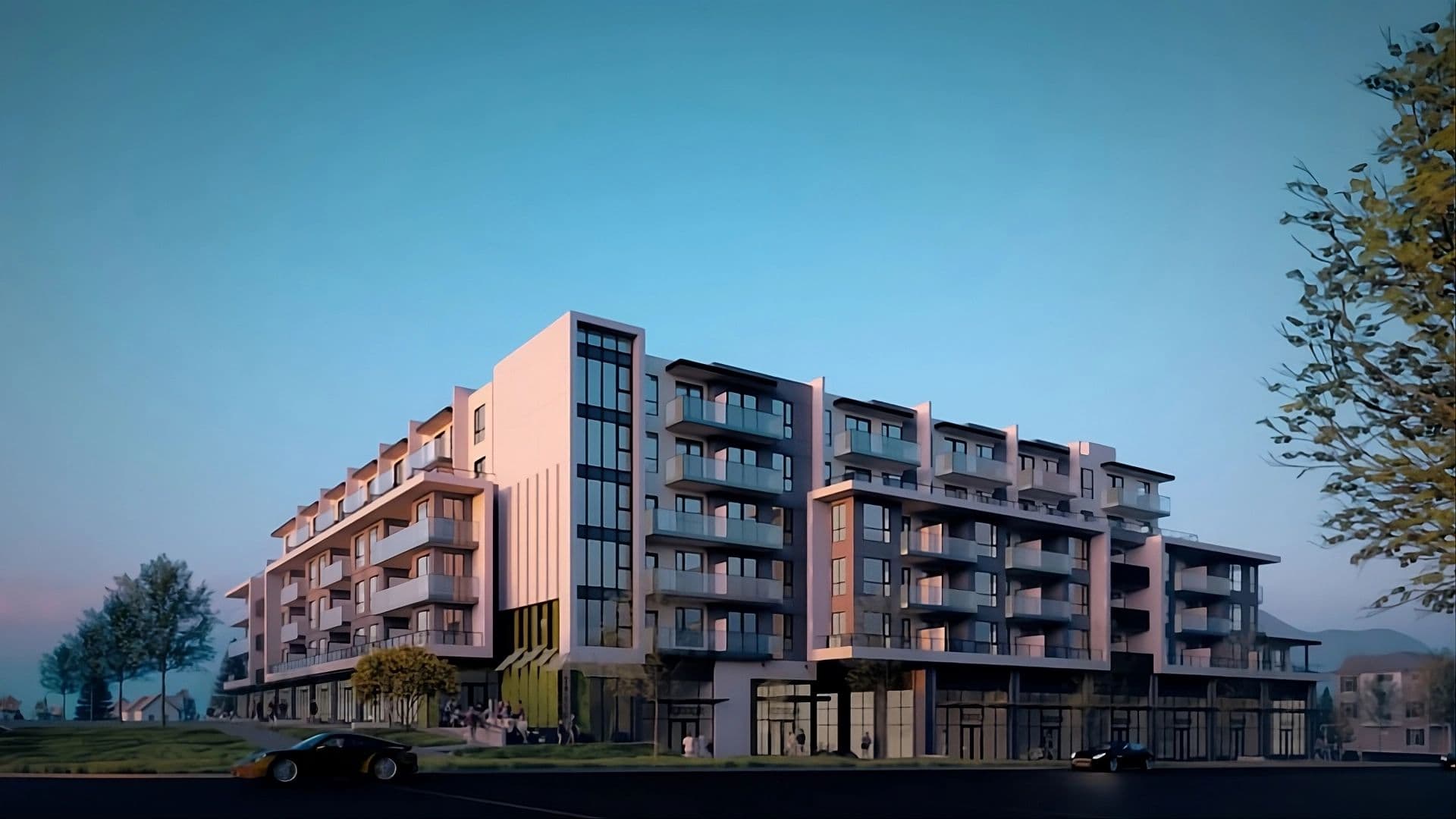 Monterey – A ground-level architectural rendering shows a modern mid-rise residential building with glass balconies, large windows, and street-level retail space under a clear dusk sky. The building is surrounded by paved streets with parked cars, landscaped lawns, and mature trees illuminated by warm, soft lighting.