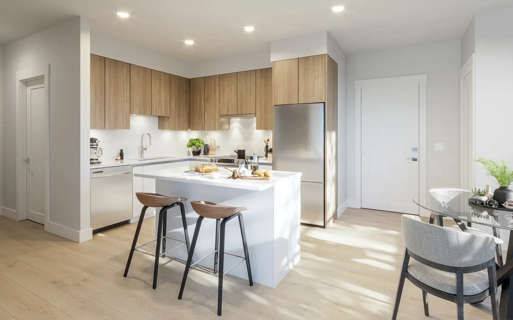 Thomas West Haney – A modern open-concept kitchen featuring light wood flat-panel upper cabinets, white quartz countertops, stainless steel appliances, and a white waterfall island with two wooden bar stools. Soft sunlight streams onto the light hardwood floors, illuminating an adjacent dining nook with a glass table.