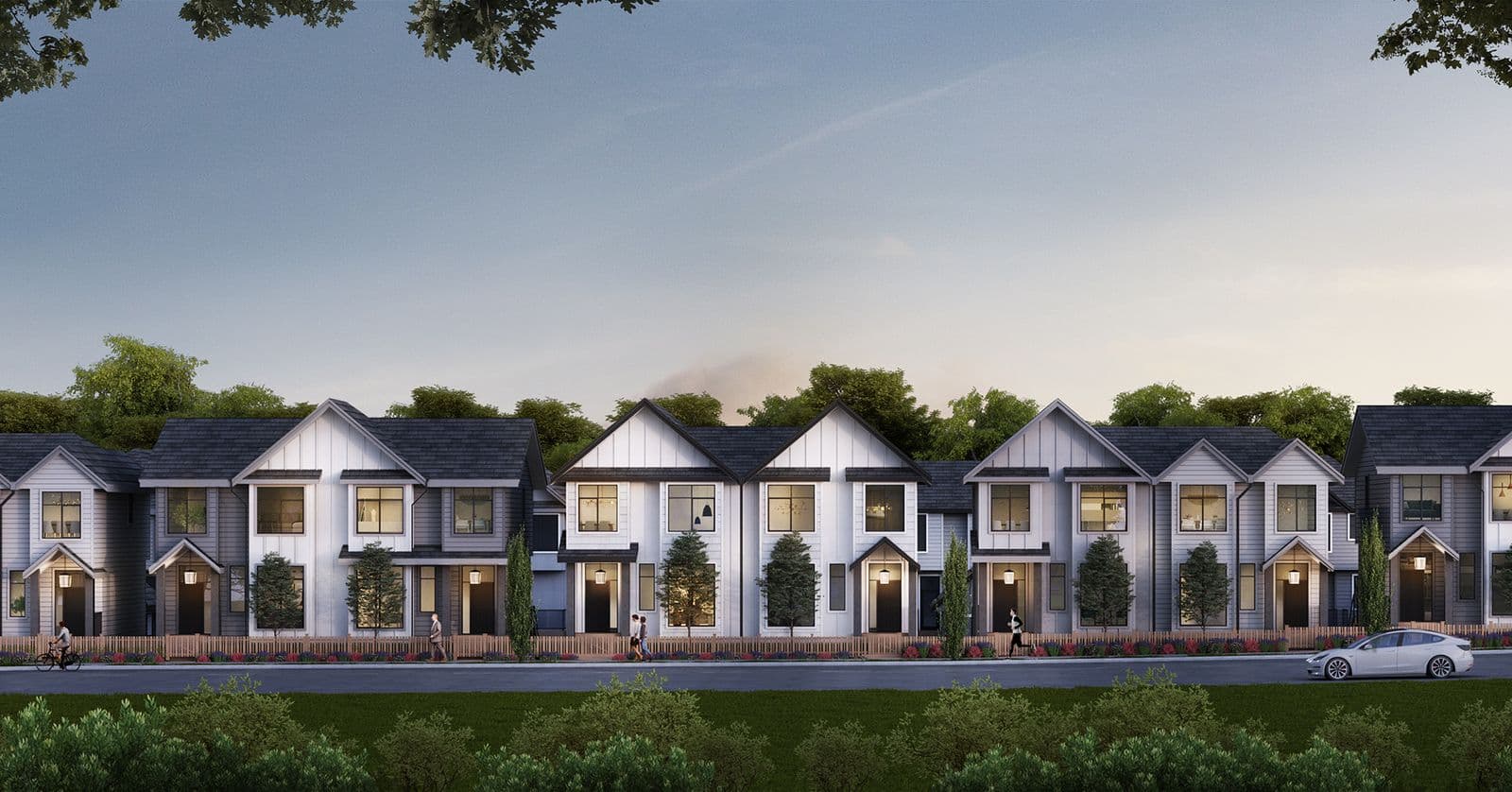 Archer at Latimer – Row of townhomes viewed from across the street at dusk, with matching gabled entries, wood fencing, and people walking and cycling in front.