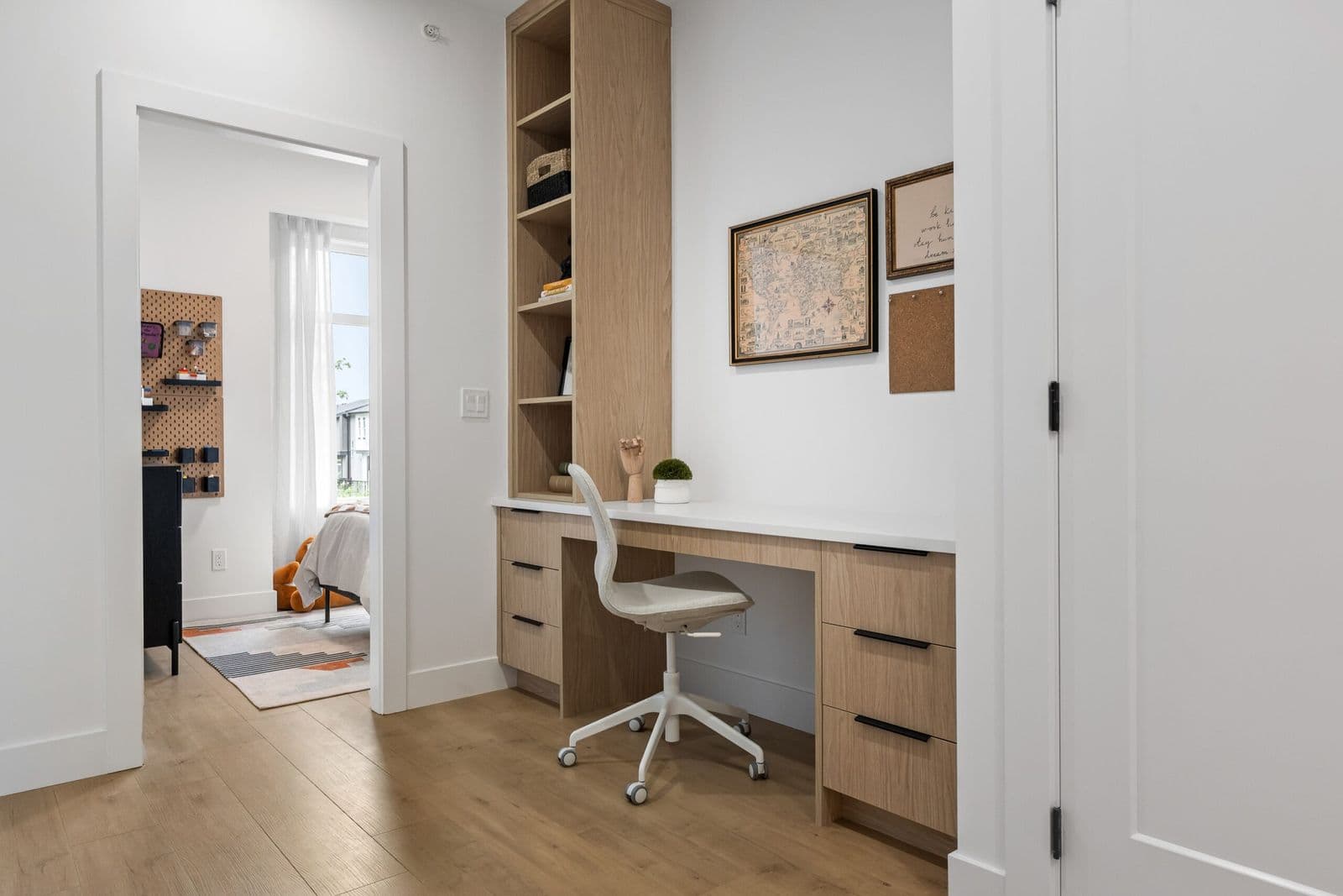 Archer at Latimer – Built-in study nook with a desk, wood shelving, and a doorway looking into a child's bedroom with a rug and stuffed toy.