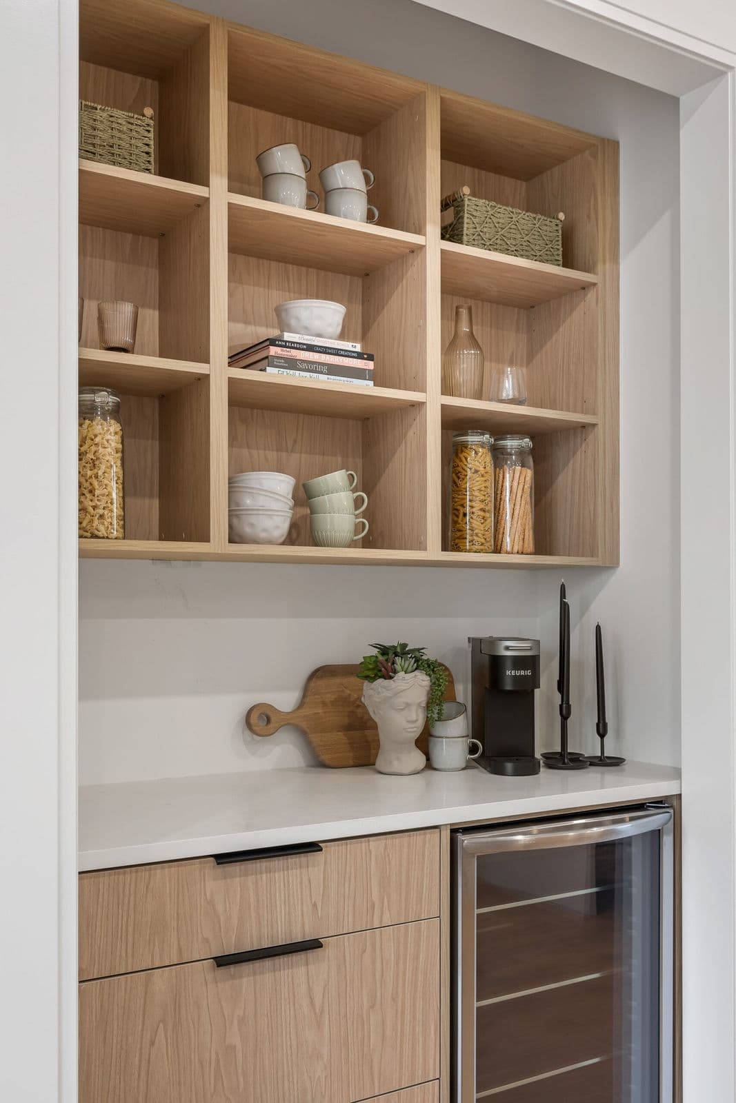 Archer at Latimer – Butler's pantry with open wood shelving holding mugs, glassware, and pantry items, a small wine fridge and Keurig machine below.