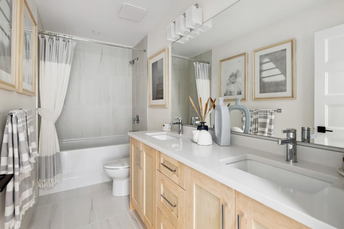 Station Grove – An open-concept kitchen with a dark navy island, white counters, rattan pendant lights, and an adjoining wood dining table set for a meal.