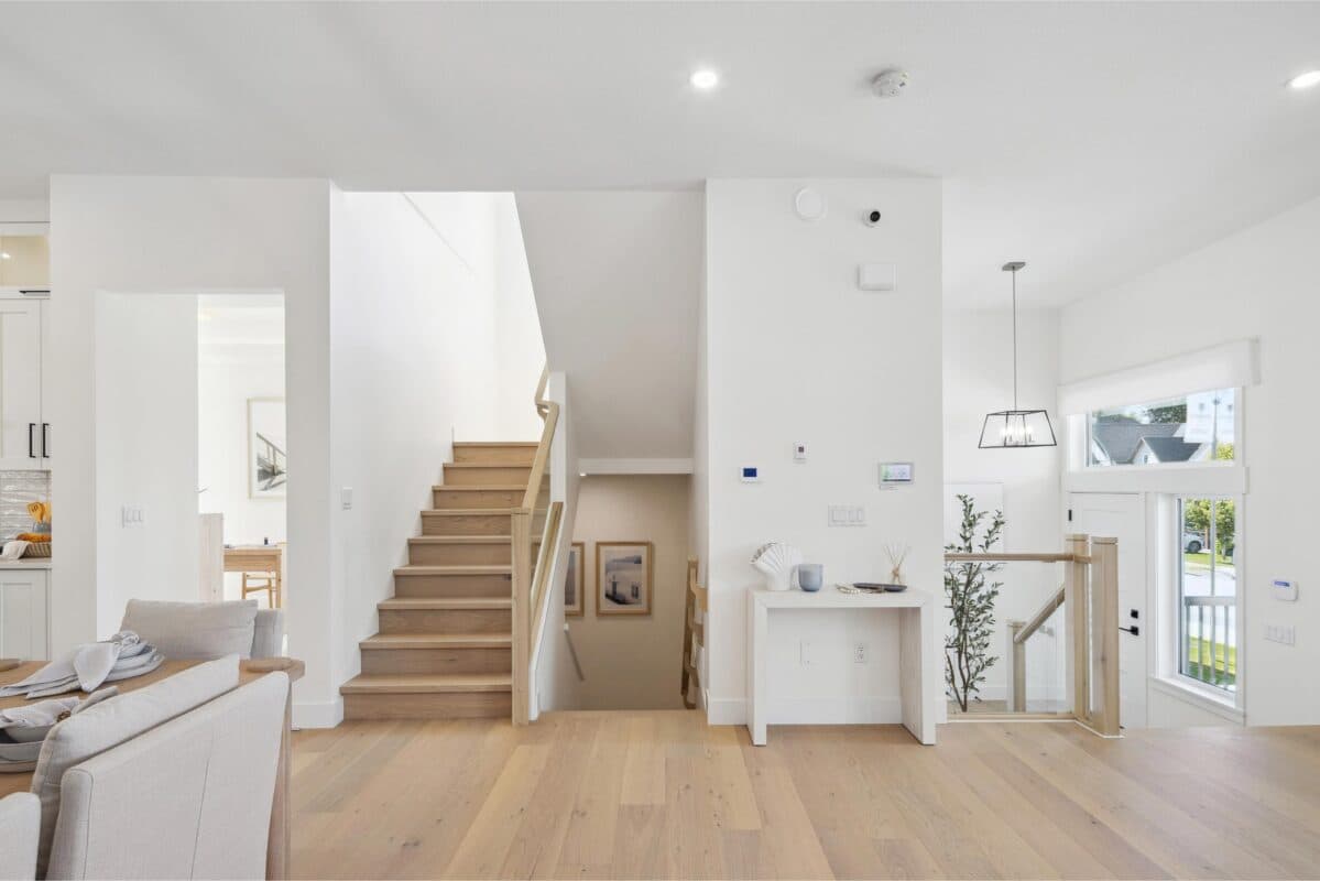 Station Grove – An entryway with a light wood staircase, framed art in an alcove, a small console table, and a glass-paned front door.