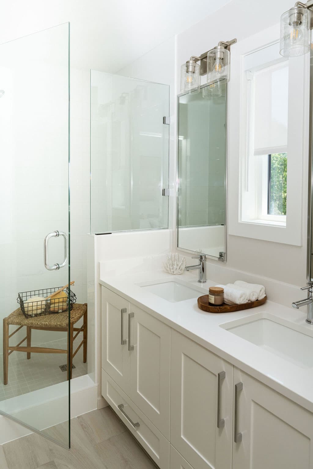 Fox and Aikins – Bathroom with a glass-enclosed shower and tub, and a double sink vanity beyond a glass partition.