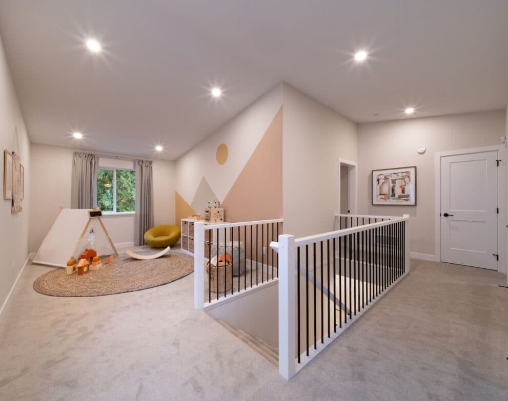 West Field at Cooper Meadows – Upstairs bonus/play room with a mountain mural accent wall, kids' teepee tent and toys, round jute rug, and a stair railing leading down.