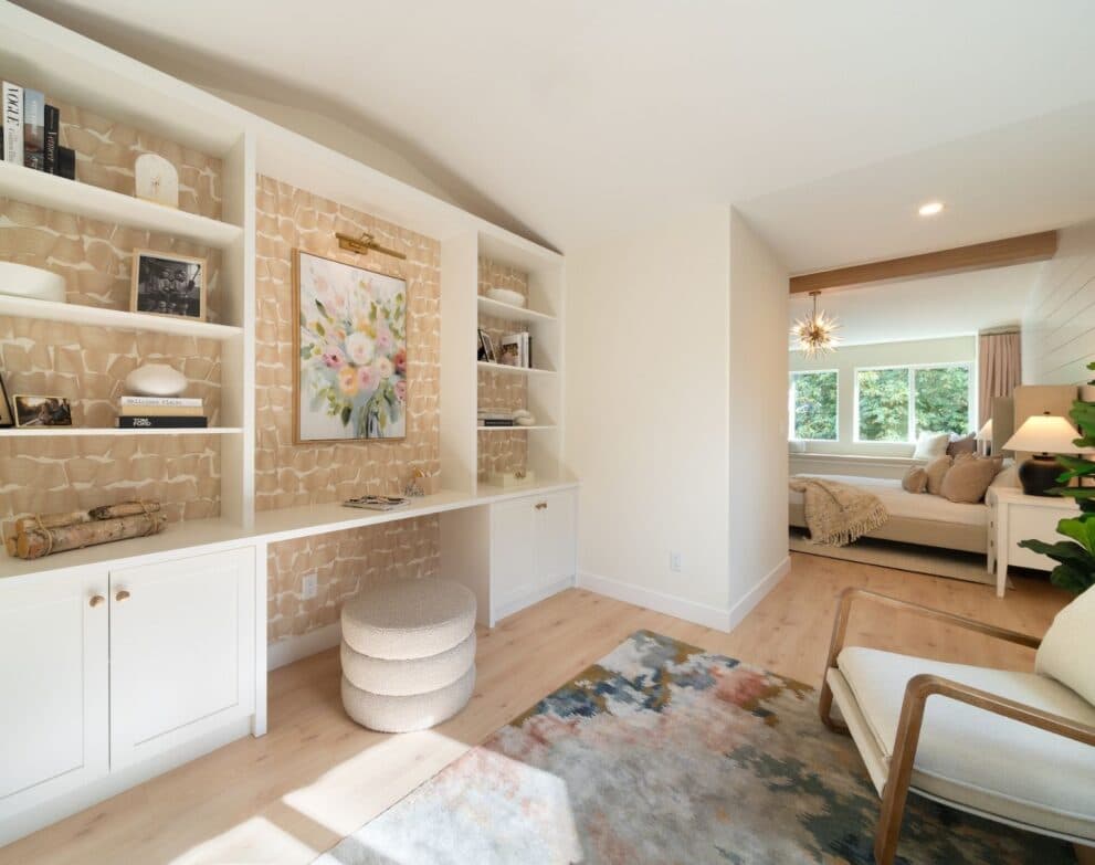 West Field at Cooper Meadows – Built-in desk and bookshelf nook with patterned wallpaper accent wall, opening into a bedroom with a window seat and sunburst chandelier visible beyond.