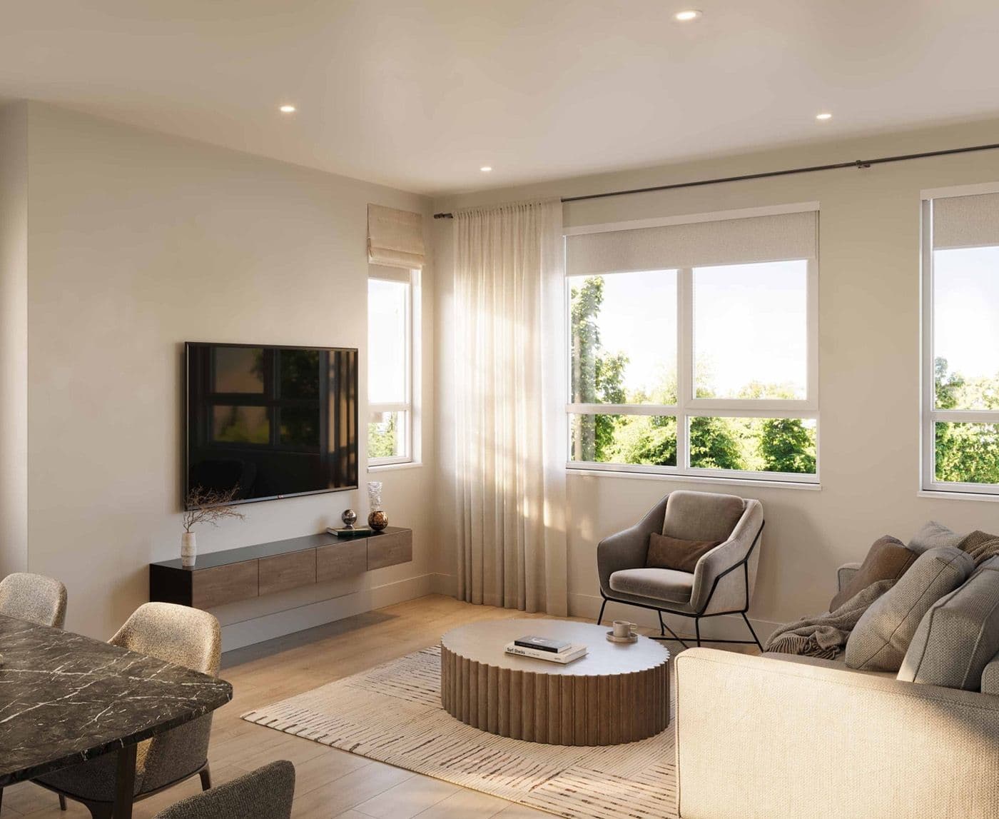 Ferndale Garden 4 – A sunlit contemporary open-concept living and dining room features light wood flooring, neutral upholstered seating, and a fluted round coffee table. Large windows draped with sheer curtains offer views of lush green trees outside, while a wall-mounted TV rests above a floating media console.