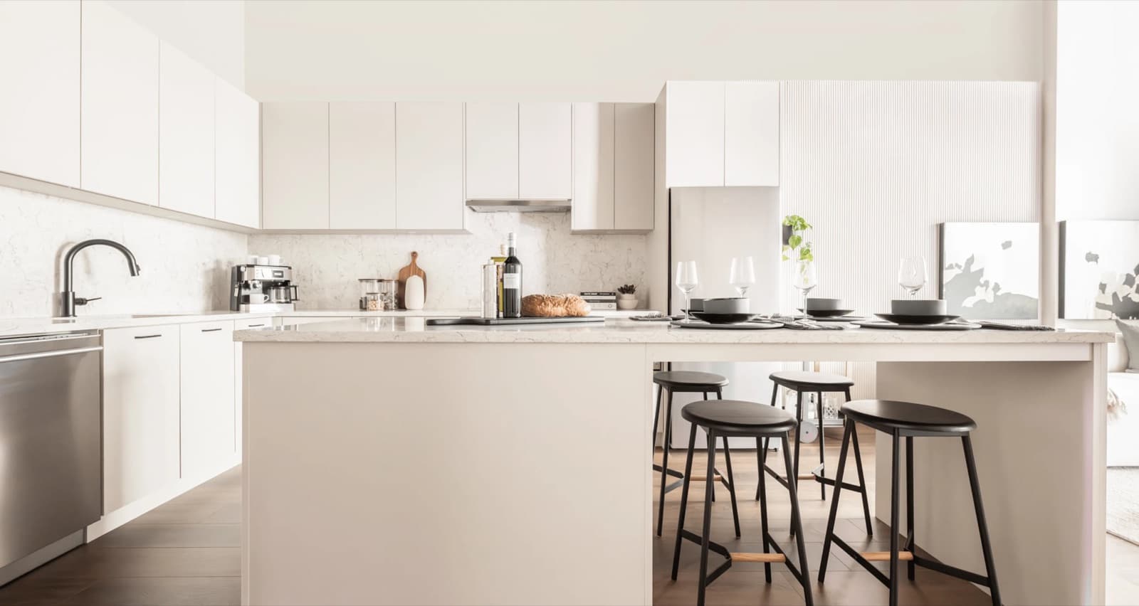 Rowan – A white kitchen island with wine and place settings, black stools, and a marble backsplash, viewed from a slightly different angle.