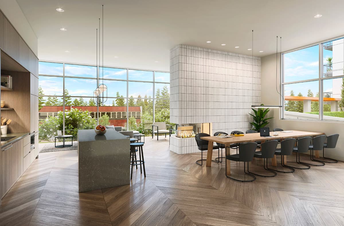 Walker House – A bright, open-concept shared lounge features chevron light-wood flooring, a long conference-style dining table, a kitchen prep area with a grey island, and a central white-tiled fireplace column. Floor-to-ceiling windows flood the space with natural daylight and offer views of lush green trees and an outdoor balcony.