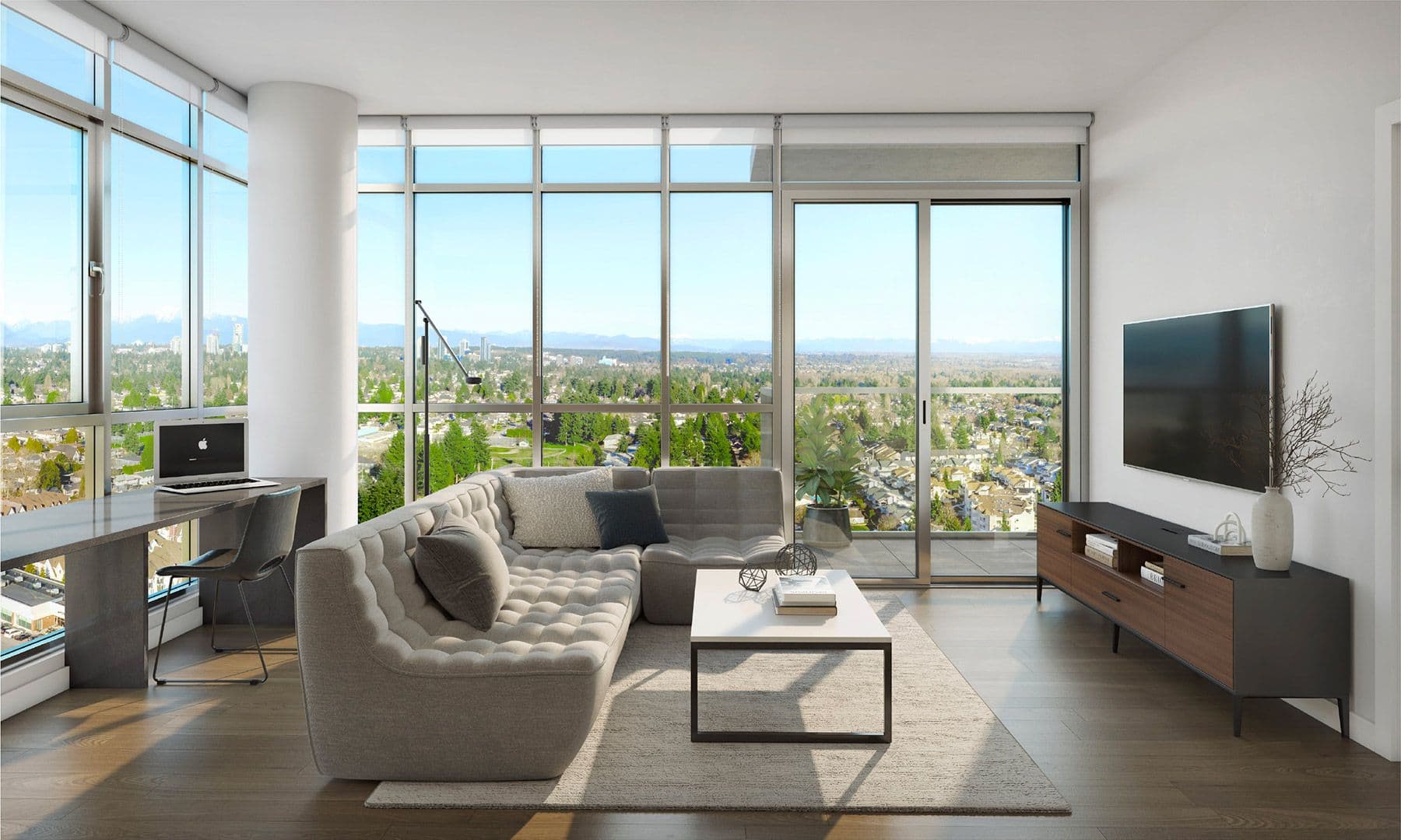 Walker House – A modern, sunlit living room featuring floor-to-ceiling corner windows that frame an expansive view of a green suburban landscape and distant mountains. The space is furnished with a tufted grey sectional sofa, a low coffee table, a sleek media console, and an integrated desk workstation near the window.
