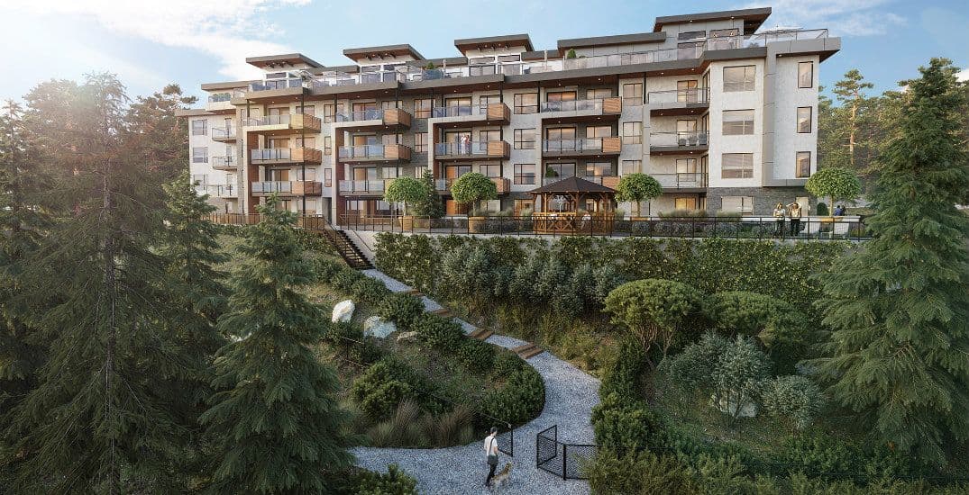 Natura – Elevated view of a multi-story residential building with wood and stone balconies overlooking a landscaped garden path and gazebo surrounded by evergreen trees.