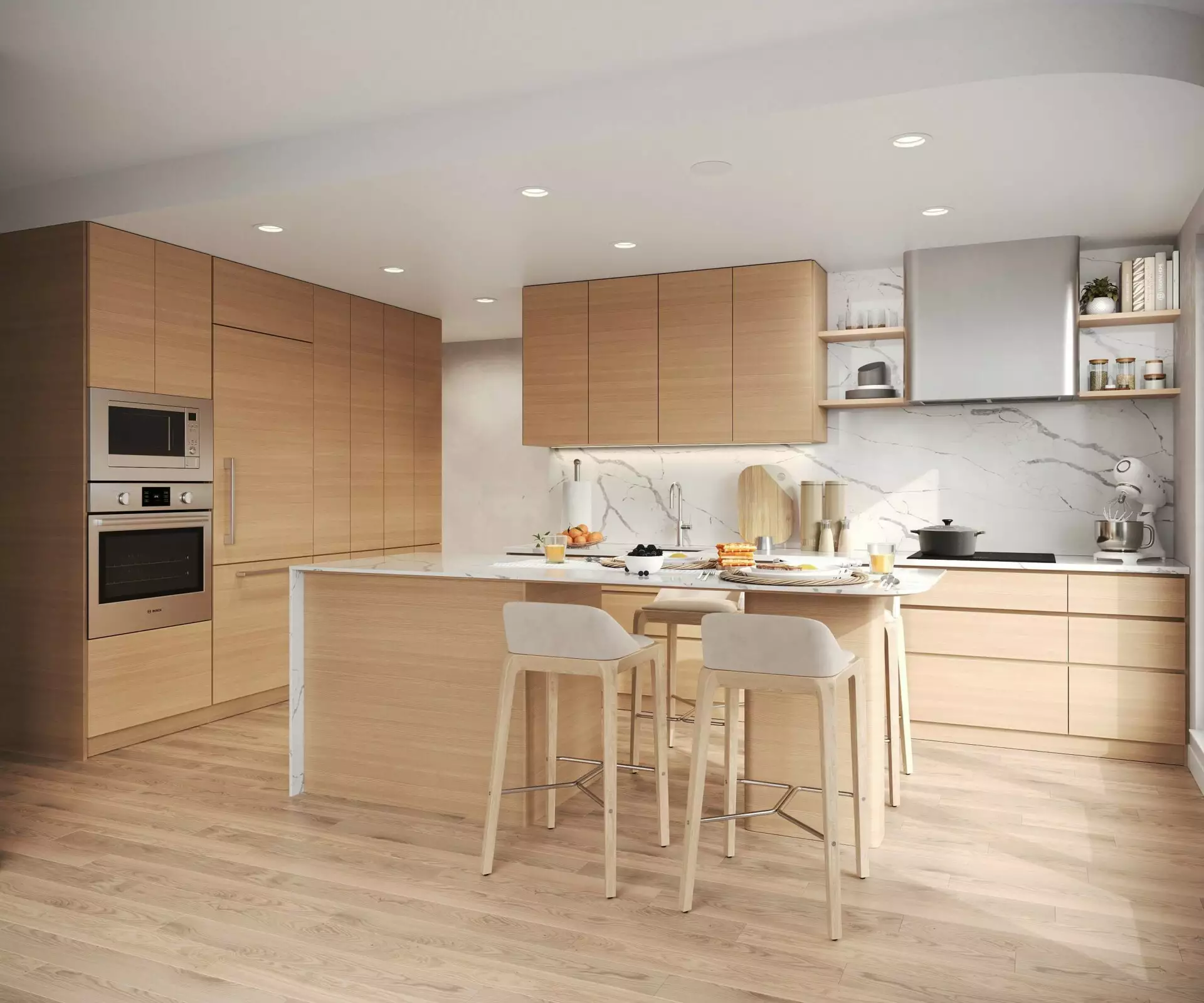 Edge Way at leləm̓ – A modern, open-concept kitchen featuring light natural wood flat-panel cabinetry, light hardwood flooring, and white marble countertops with matching full-height backsplash. A central kitchen island with seating includes counter stools and a breakfast spread, complemented by integrated stainless steel appliances and recessed ceiling lighting.