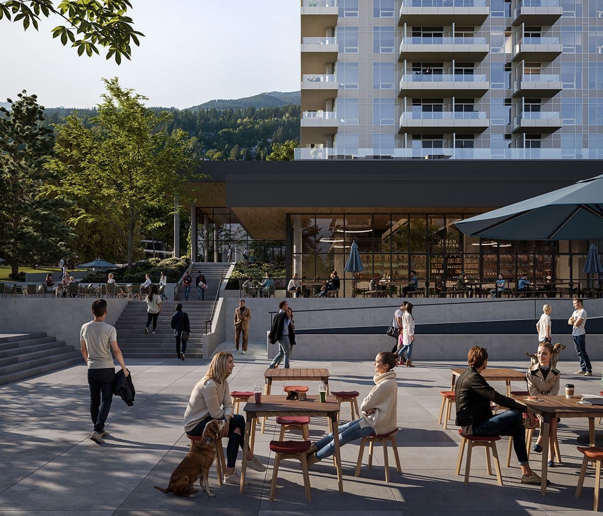 Inlet District – A bustling, sunlit pedestrian plaza at the base of a modern mid-rise residential building features outdoor cafe seating, broad concrete stairs, and people walking with pets. The ground level hosts retail and an open cafe space beneath large glass windows, with lush green trees and forested mountains visible in the background under a bright daytime sky.