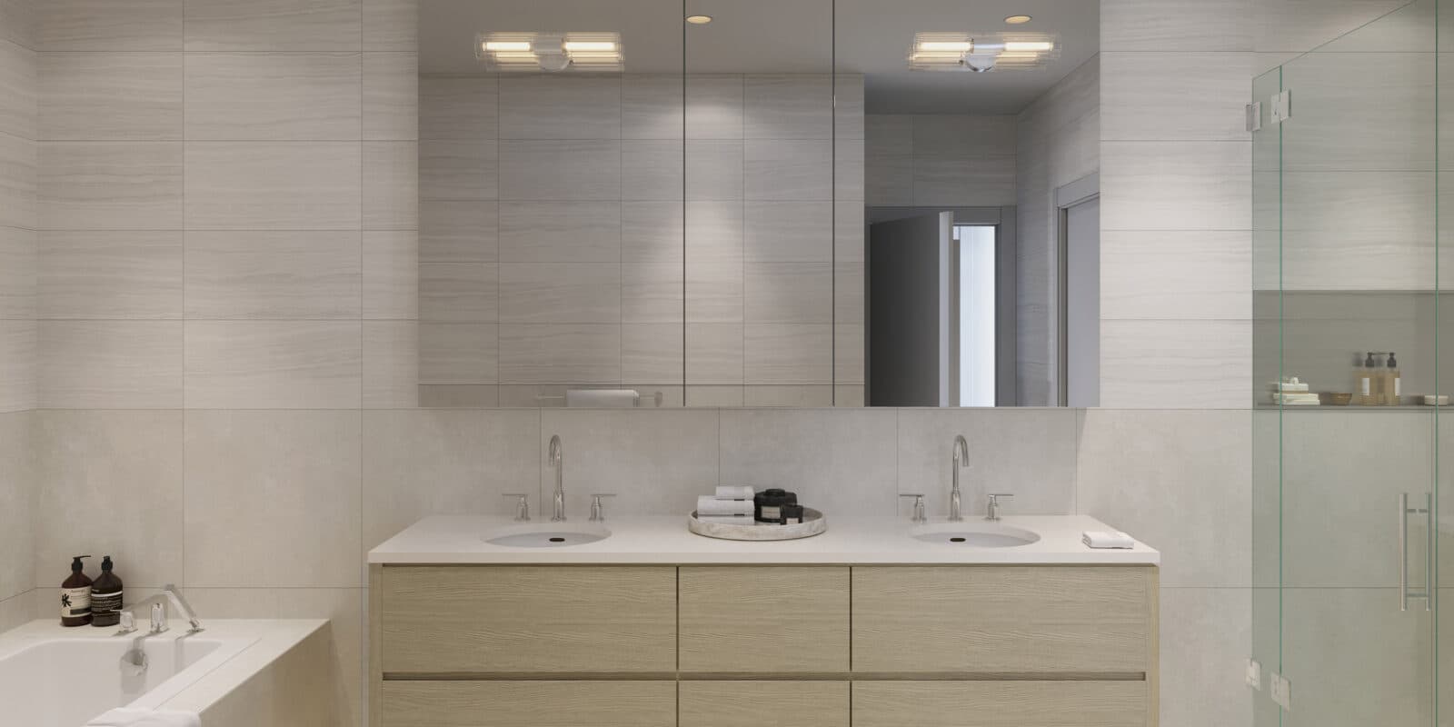 Wildwood at Uplands – Bathroom with a wood double vanity, large mirrored medicine cabinets, a freestanding soaking tub, and a glass-enclosed shower with storage niche.