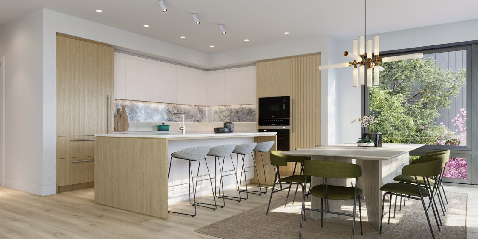 Wildwood at Uplands – Open kitchen and dining area with wood and white cabinetry, an island with gray stools, and a dining table with olive green chairs near a window to greenery.