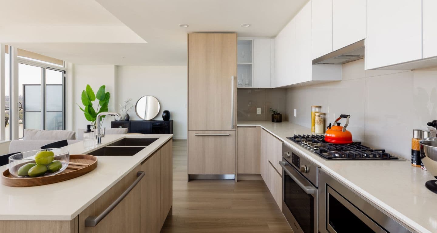 618 Carnarvon – Kitchen with a light wood island featuring double sinks, integrated wood-panel refrigerator, white upper cabinets, and a gas cooktop with stainless range hood.