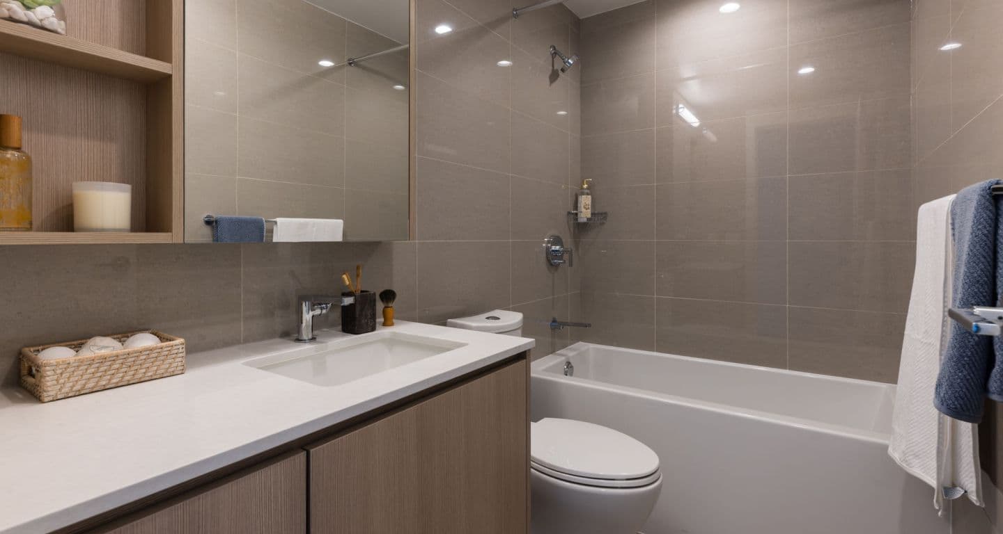 618 Carnarvon – Bathroom with a glass-enclosed tub/shower combo, grey tile walls, a wood vanity with white countertop, and a mirrored medicine cabinet.