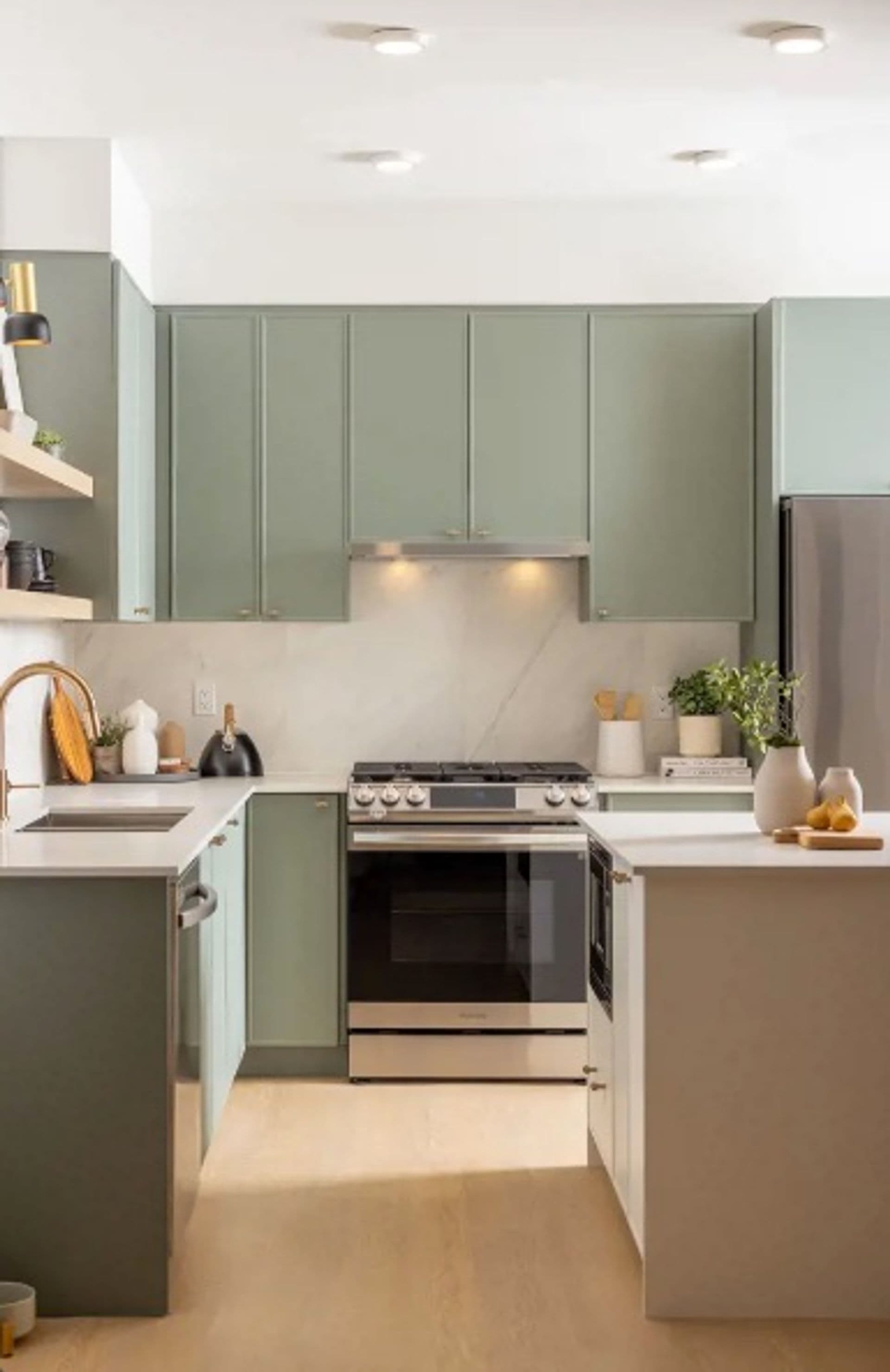 Bastille – U-shaped kitchen with sage green cabinets, a marble backsplash, gas range, stainless fridge, and two islands with white countertops.