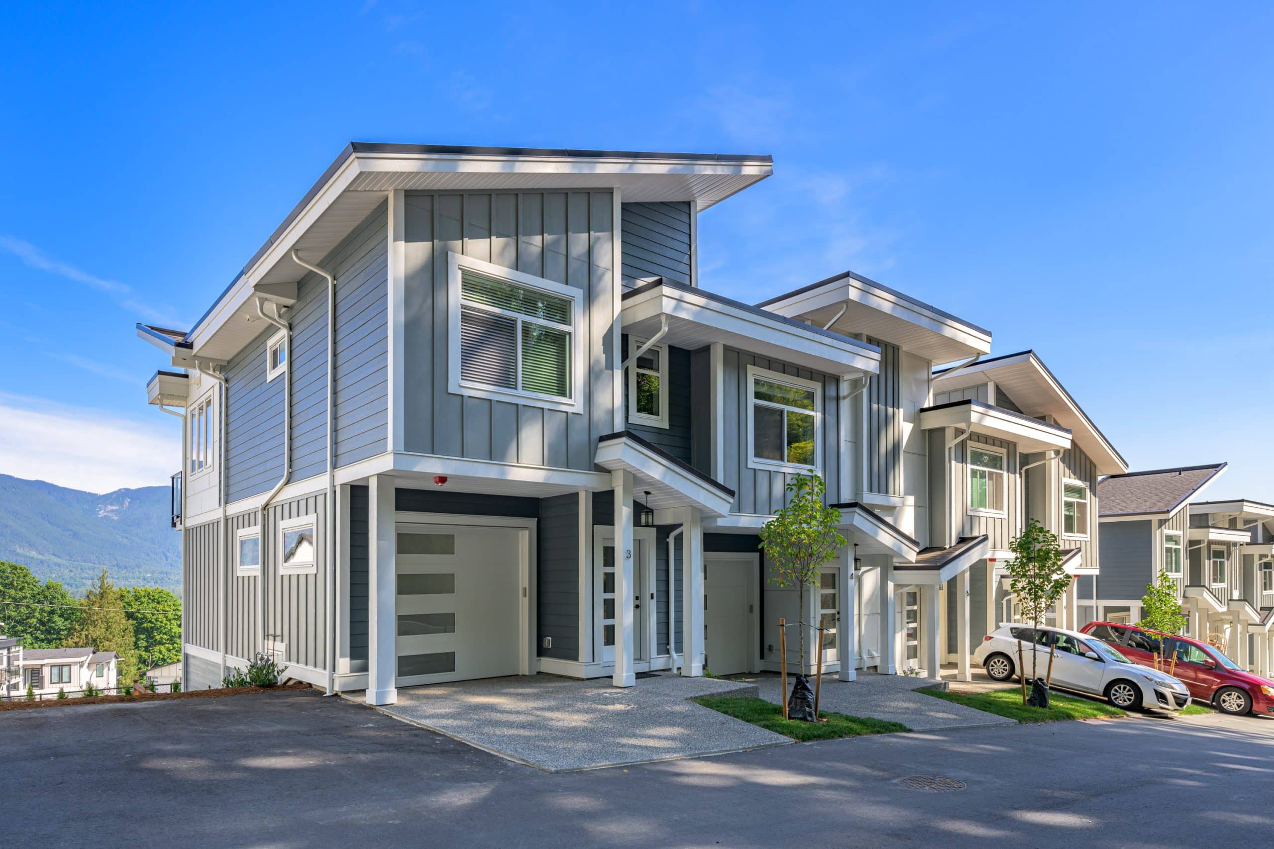 Osprey Ridge – Daytime street view of the two-story townhome building with gray siding, white trim, and a row of individual garage doors and entrances.