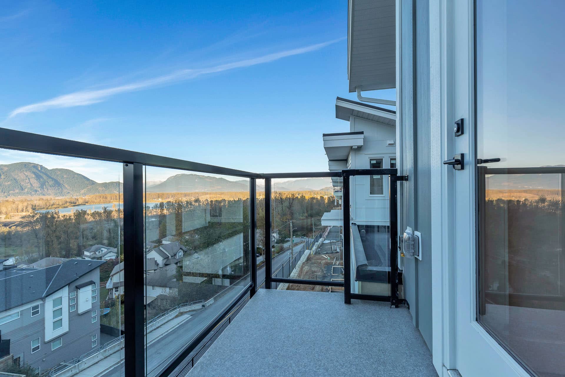 Osprey Ridge – View from a balcony overlooking a river valley, farmland, and distant mountains under a clear blue sky.