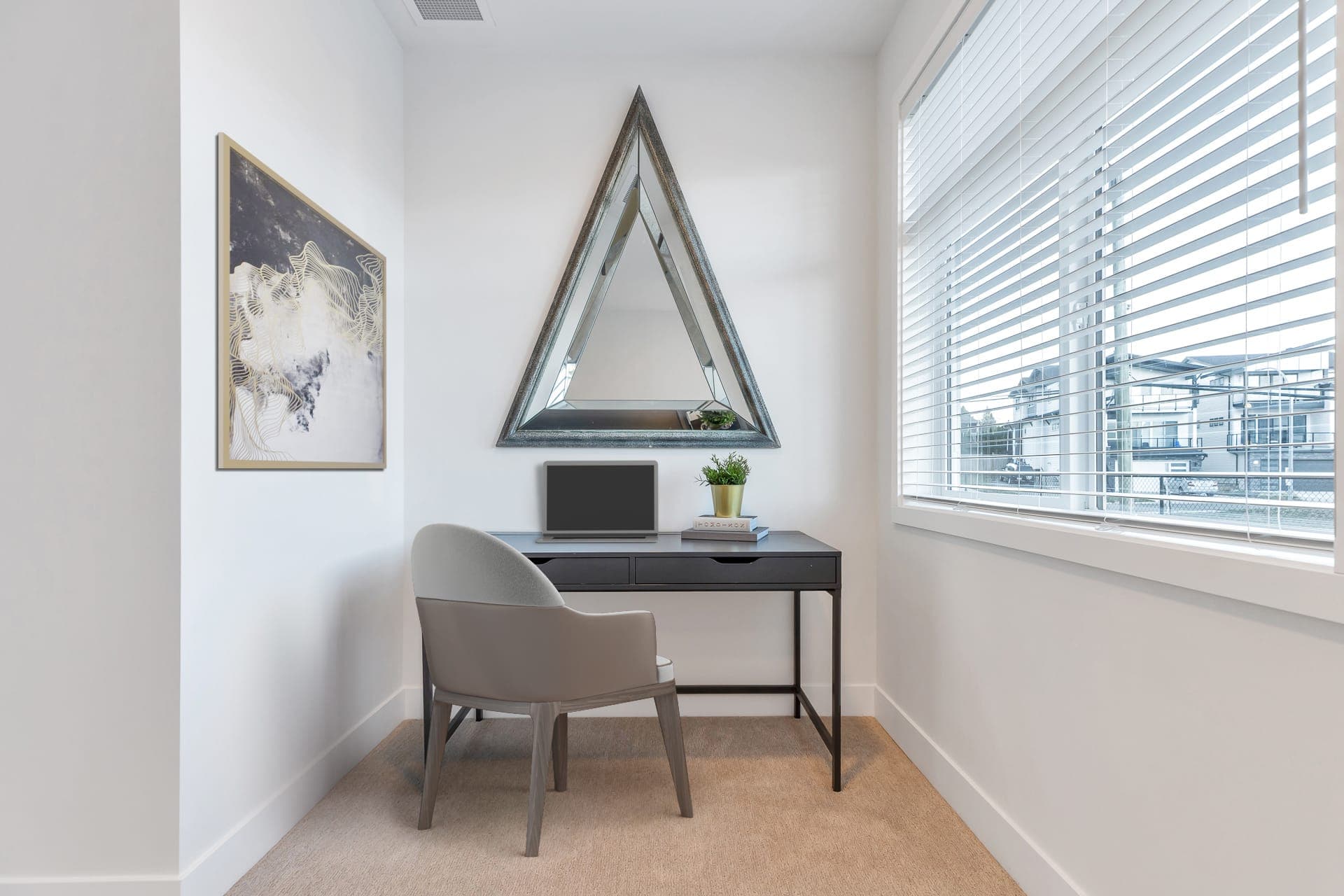 Osprey Ridge – Small home office nook with a dark desk, laptop, chair, and a triangular mirror mounted on the wall.