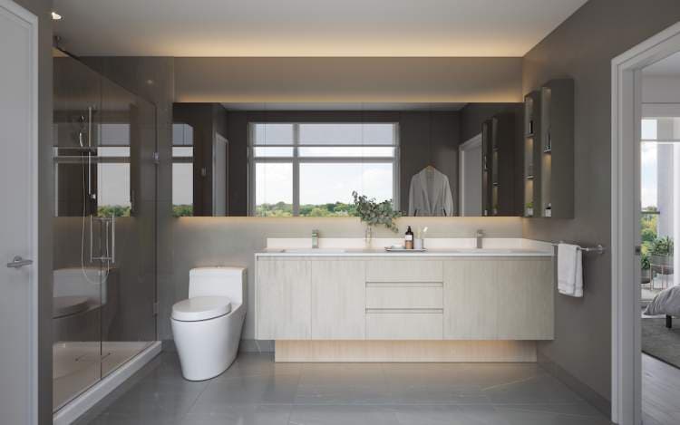 Clive at Collingwood Condos – Bathroom with a double vanity, large mirror, glass shower, and a window overlooking greenery.
