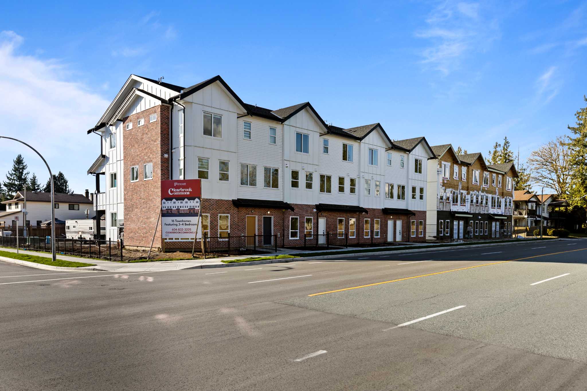 Clearbrook Commons – Street-level view of the Clearbrook Commons three-story townhome building facade featuring brick and white siding.