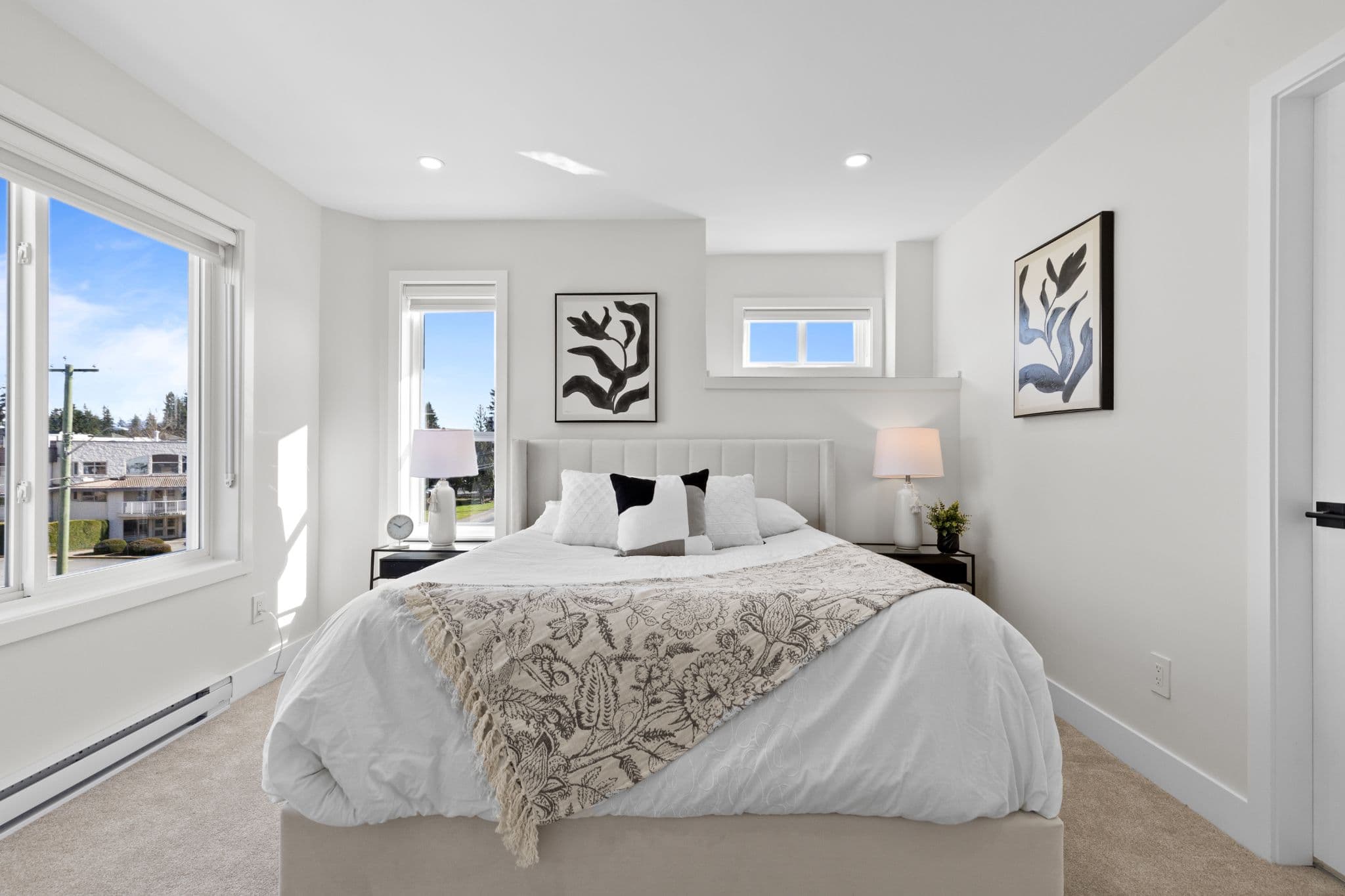 Clearbrook Commons – Bedroom with king bed, neutral bedding, bedside tables with lamps, wall art, and large bright window.