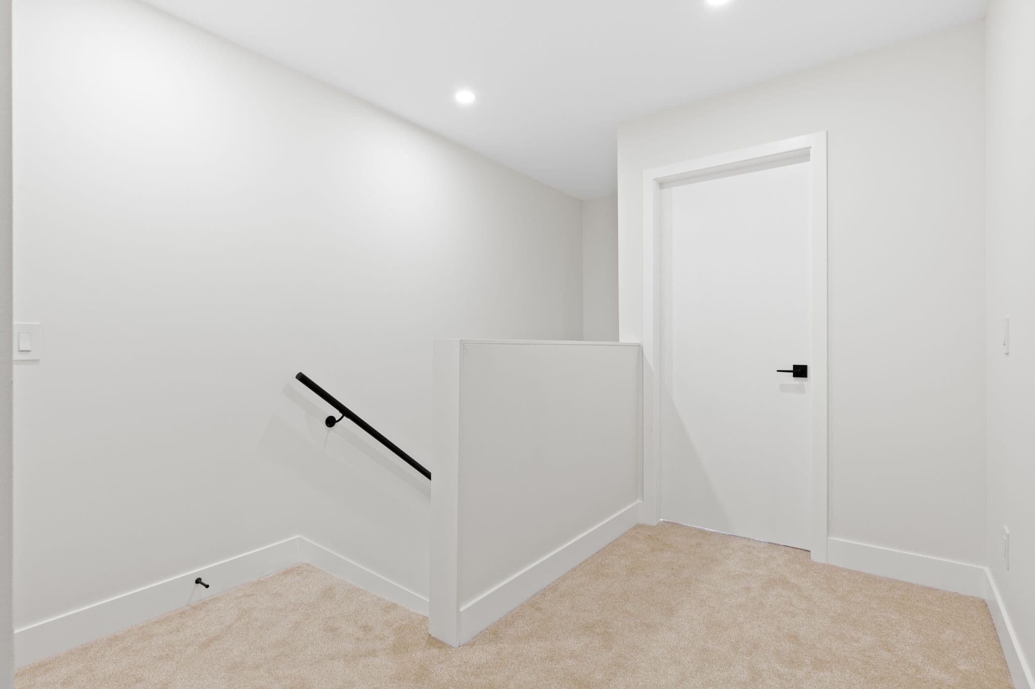 Clearbrook Commons – Upper hallway landing with carpeted floor, white interior doors with black handles, and half-wall stair opening.