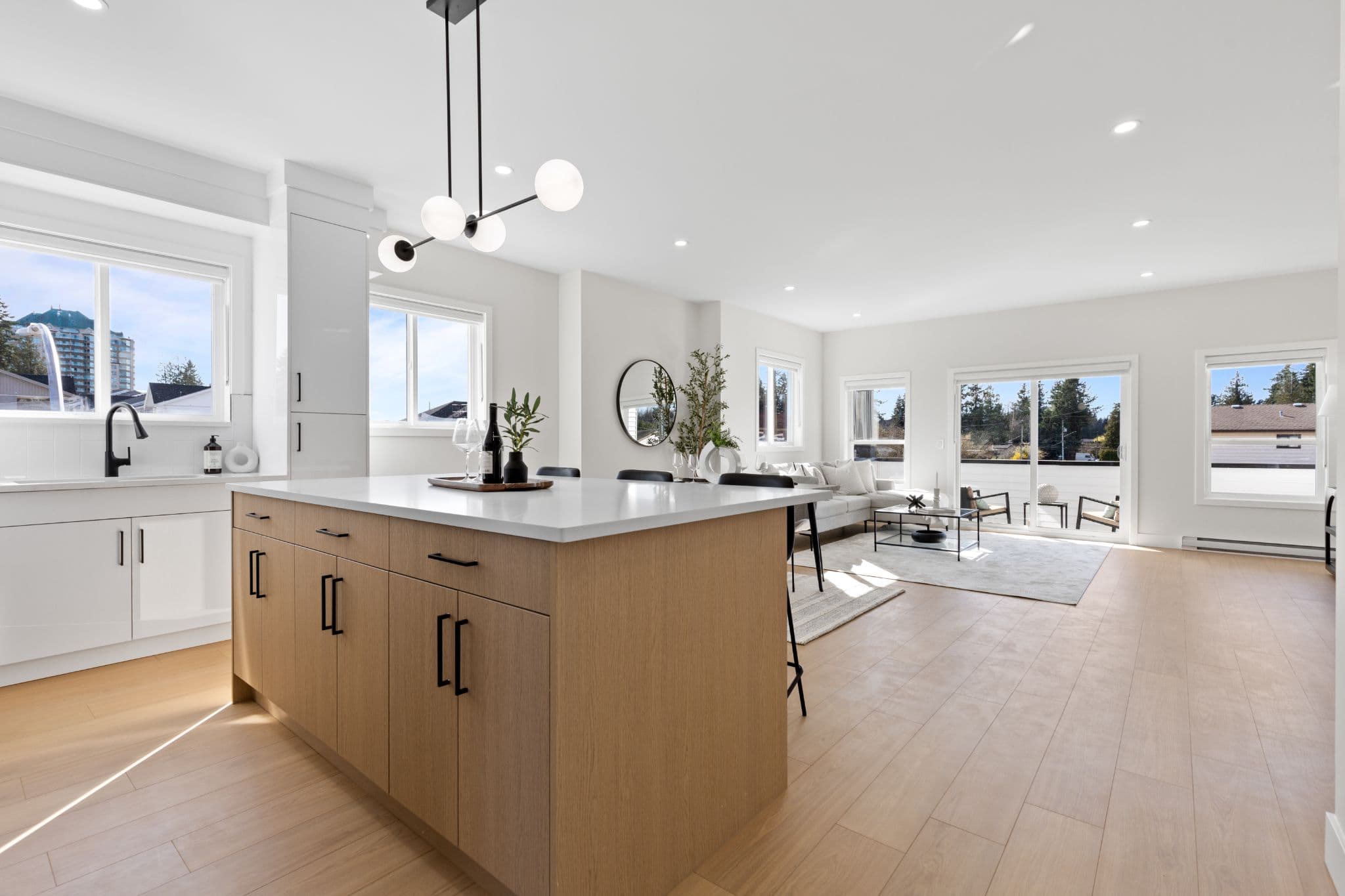 Clearbrook Commons – Spacious open kitchen island overlooking the living area with sliding patio doors leading out to a balcony.
