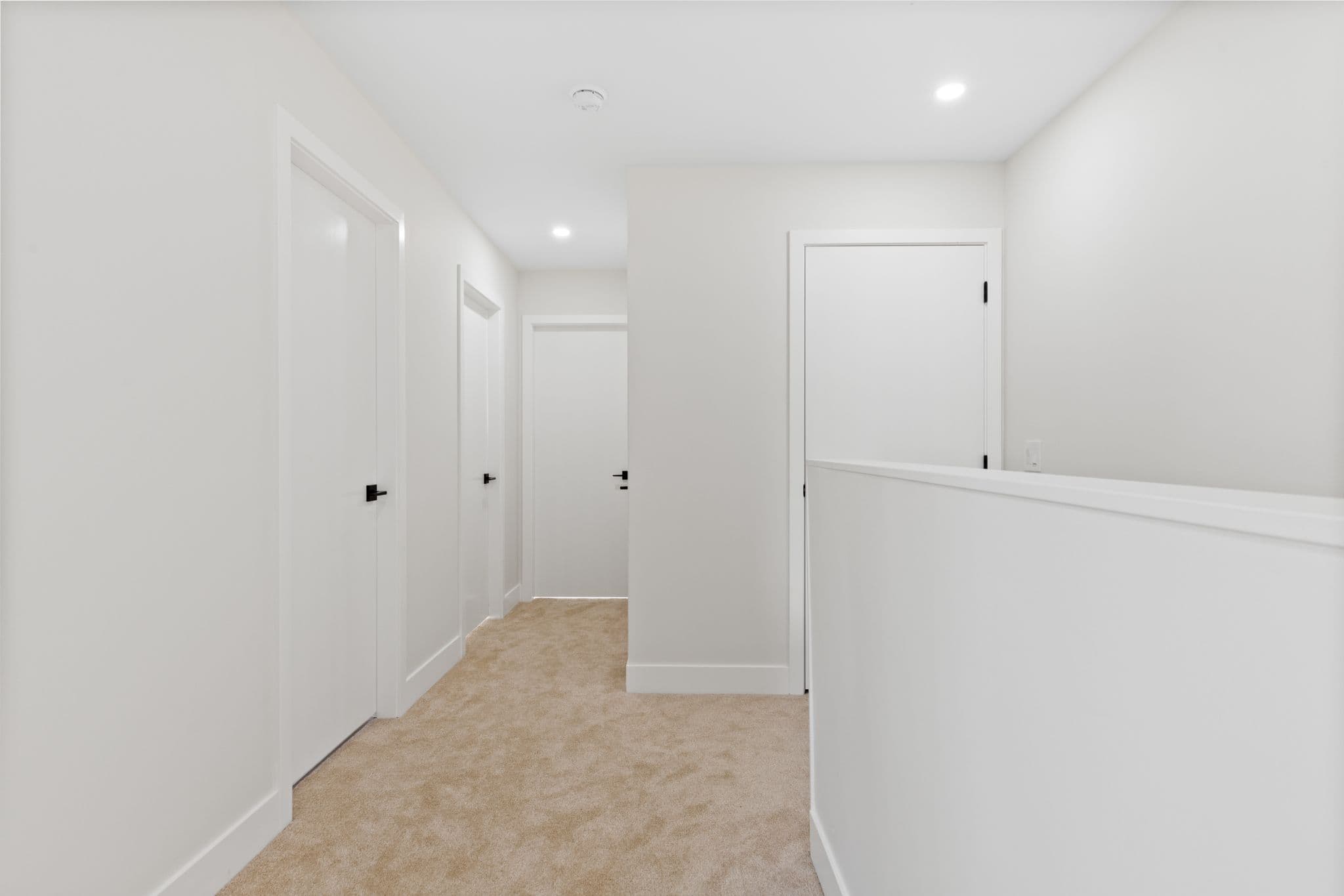 Clearbrook Commons – Carpeted hallway on upper level with multiple white doors and modern recessed lighting.