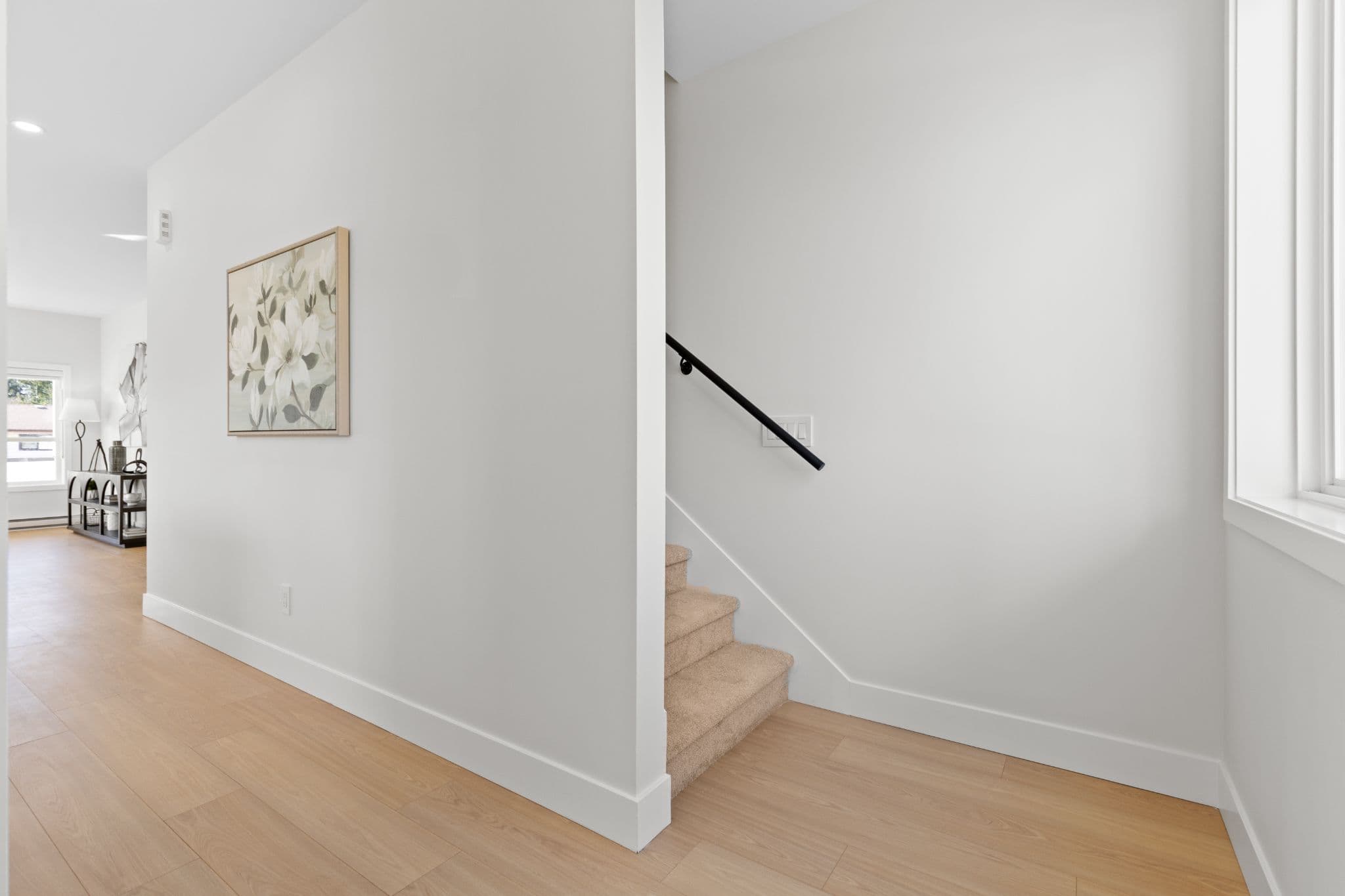 Clearbrook Commons – Staircase alcove with carpeted steps, white walls, black handrail, and wood flooring.