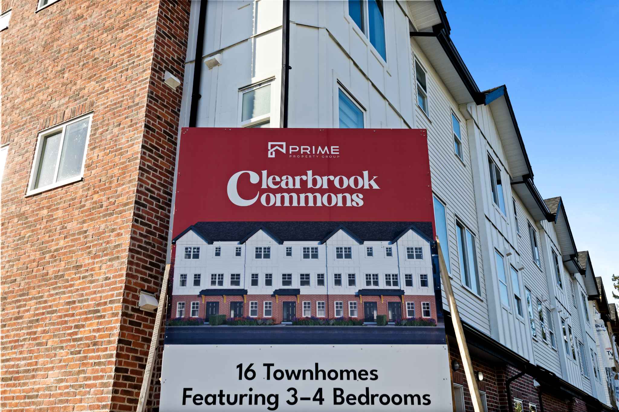 Clearbrook Commons – Promotional sign for Clearbrook Commons townhomes standing in front of the exterior building wall.