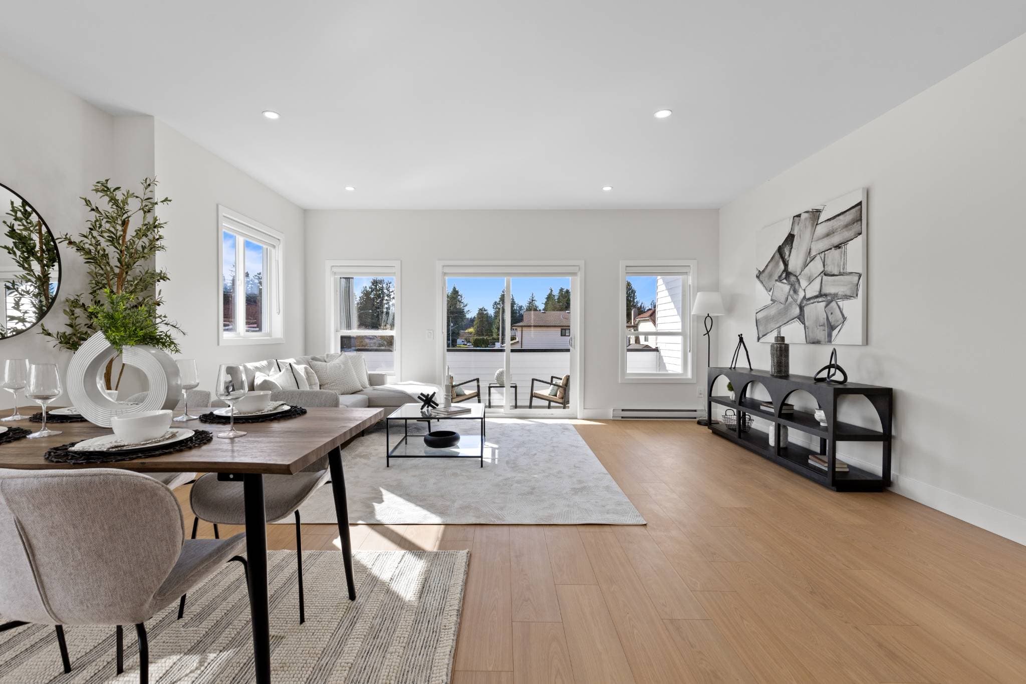 Clearbrook Commons – Bright open living and dining space with light wood floors and sliding glass door to an outdoor balcony.