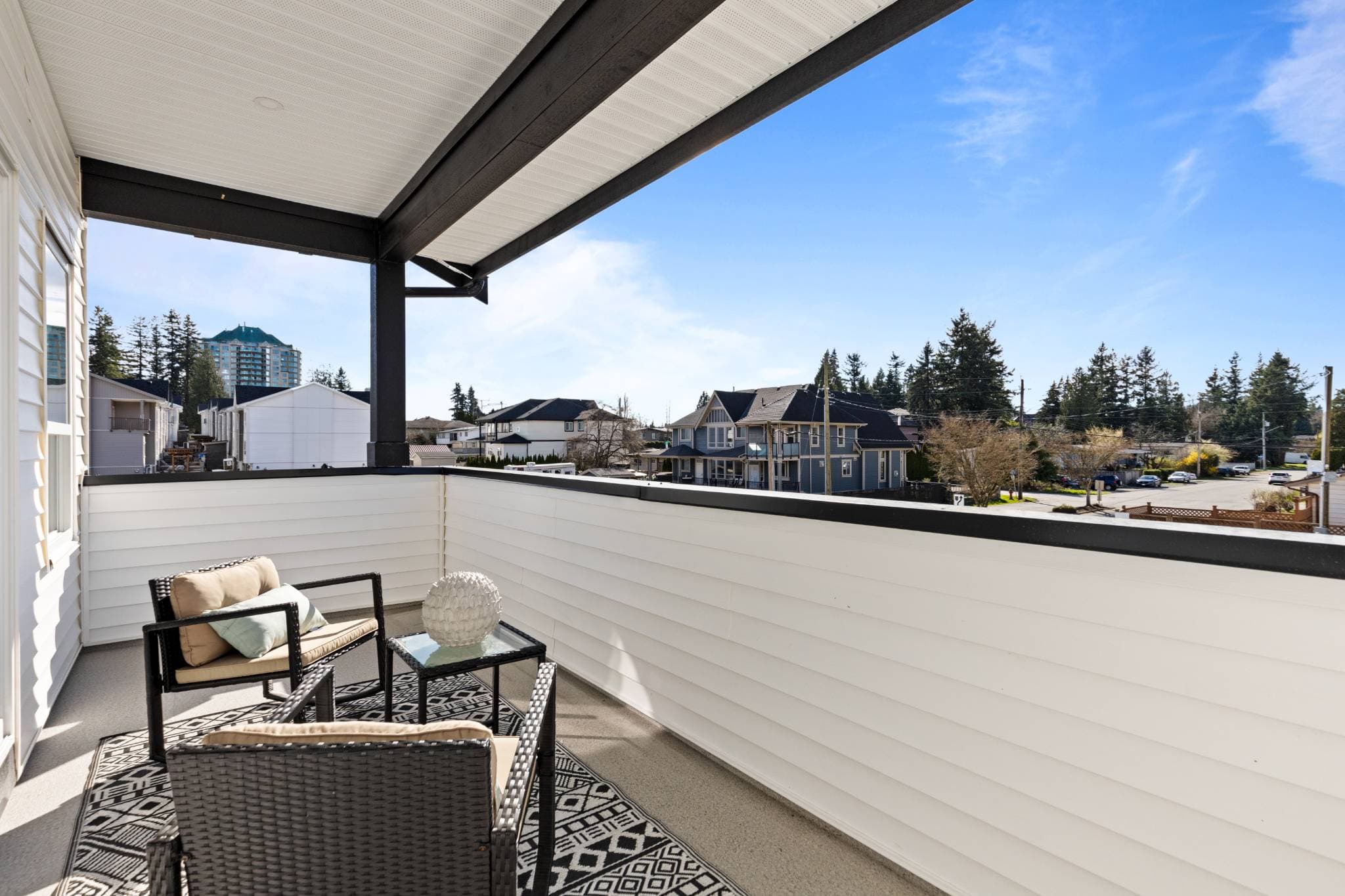 Clearbrook Commons – Covered outdoor balcony with seating, small glass table, patterned rug, and view of the surrounding neighborhood.