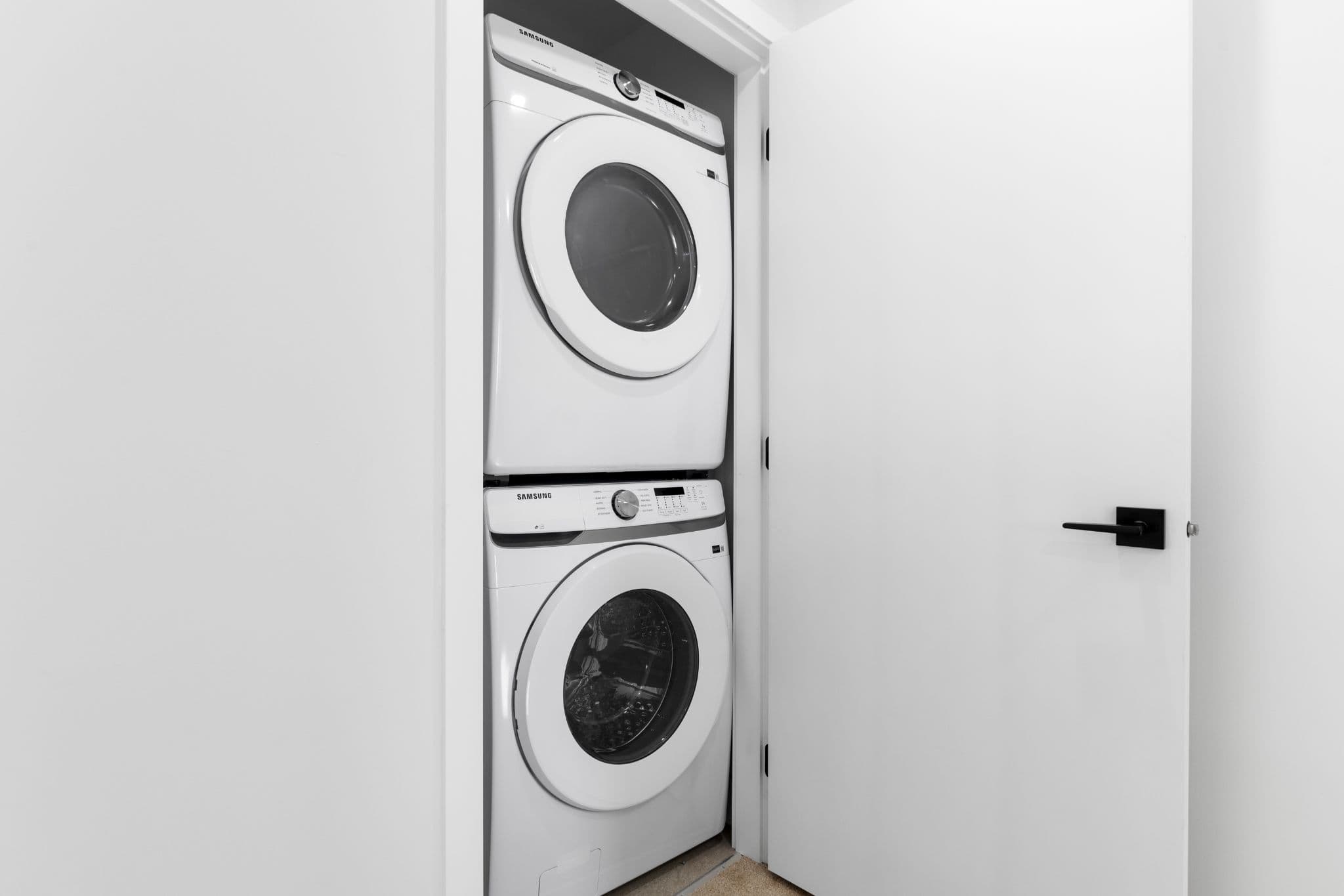 Clearbrook Commons – Laundry closet containing stacked Samsung front-loading washer and dryer behind an open white door.