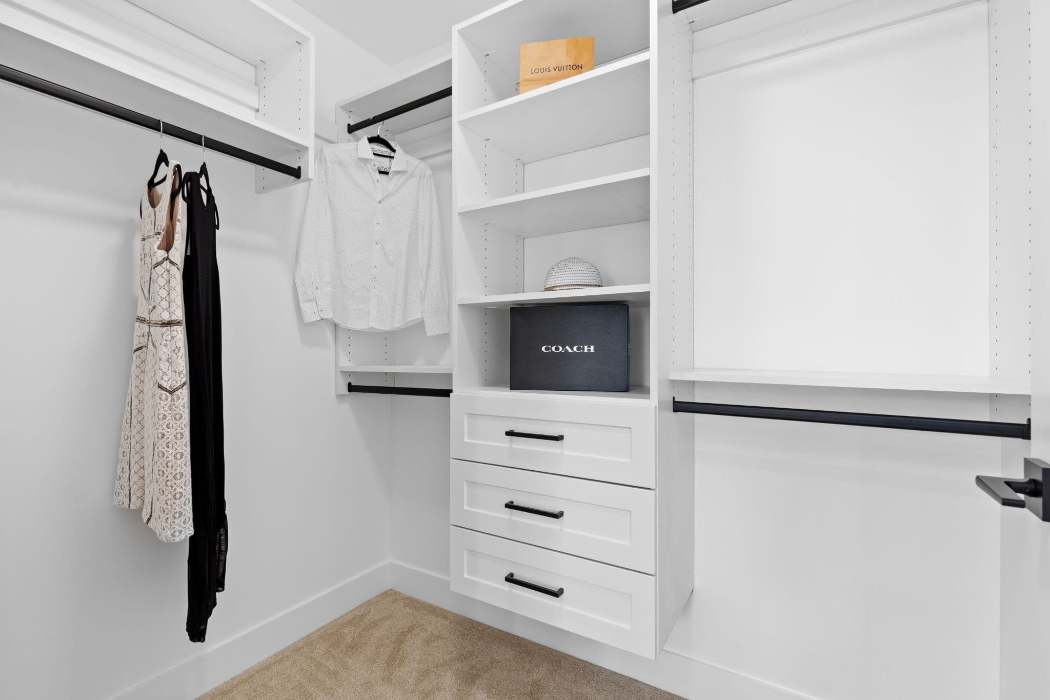 Clearbrook Commons – Walk-in closet featuring white built-in shelving, drawers, and hanging space.