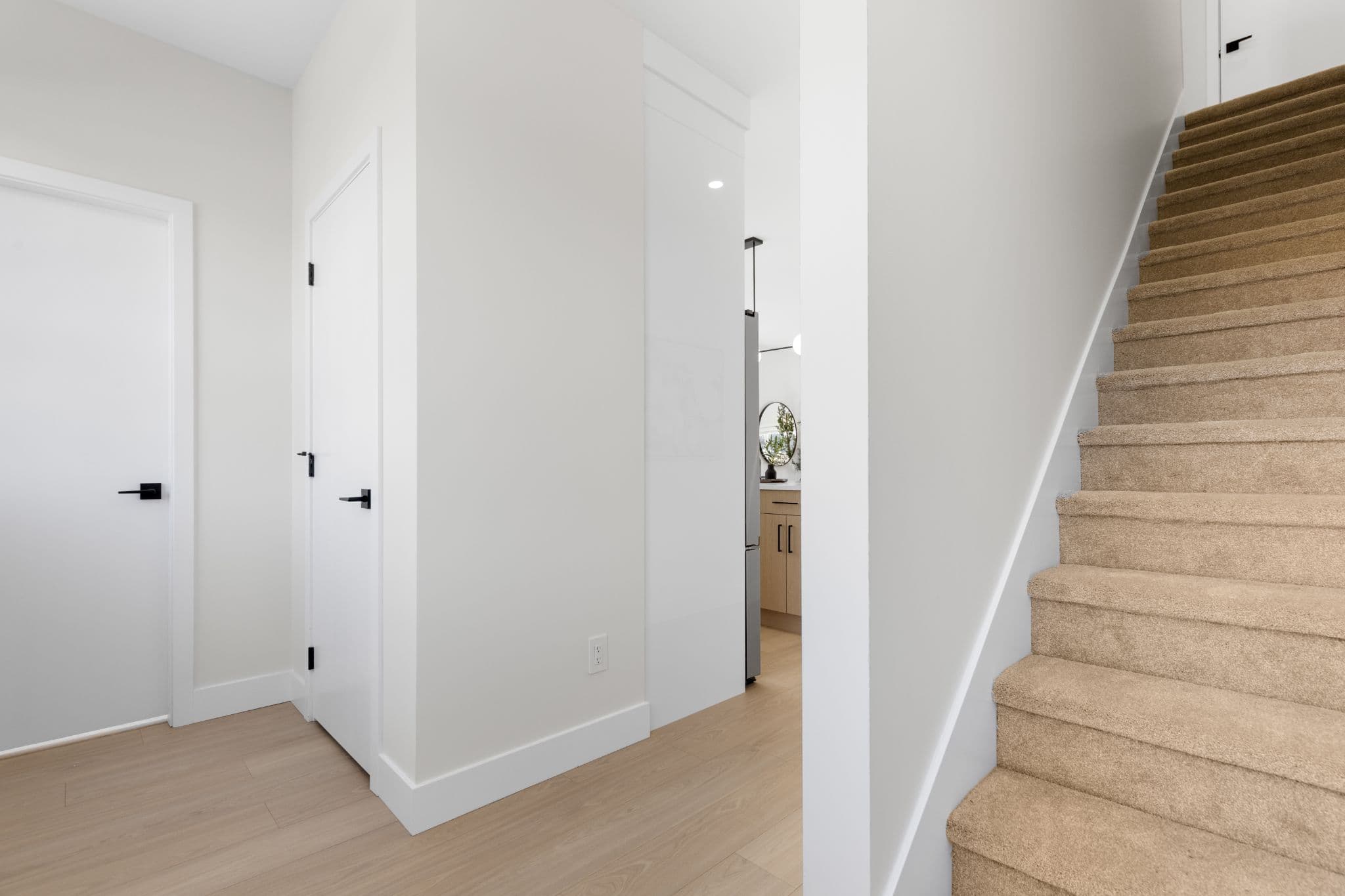 Clearbrook Commons – Foyer entrance area showing wood laminate floor, white front door with black hardware, and carpeted stairs leading up.