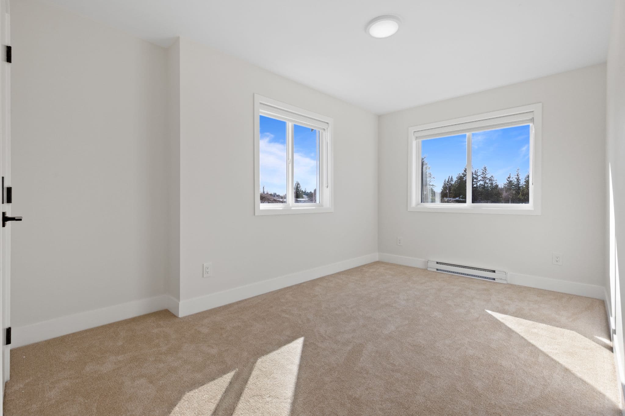 Clearbrook Commons – Empty bedroom interior with wall-to-wall carpeting, white walls, and two windows.