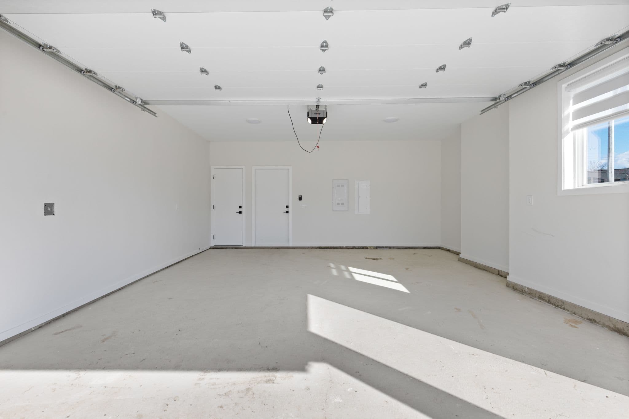 Clearbrook Commons – Clean empty garage space with concrete flooring, automatic garage opener, and interior access doors.