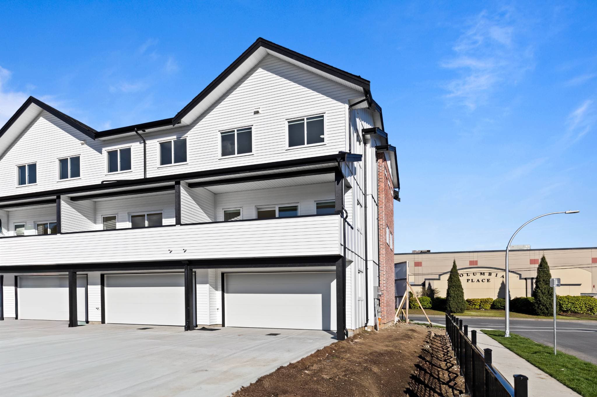 Clearbrook Commons – Exterior view of the garage entrances and white siding upper balconies of the townhome development.